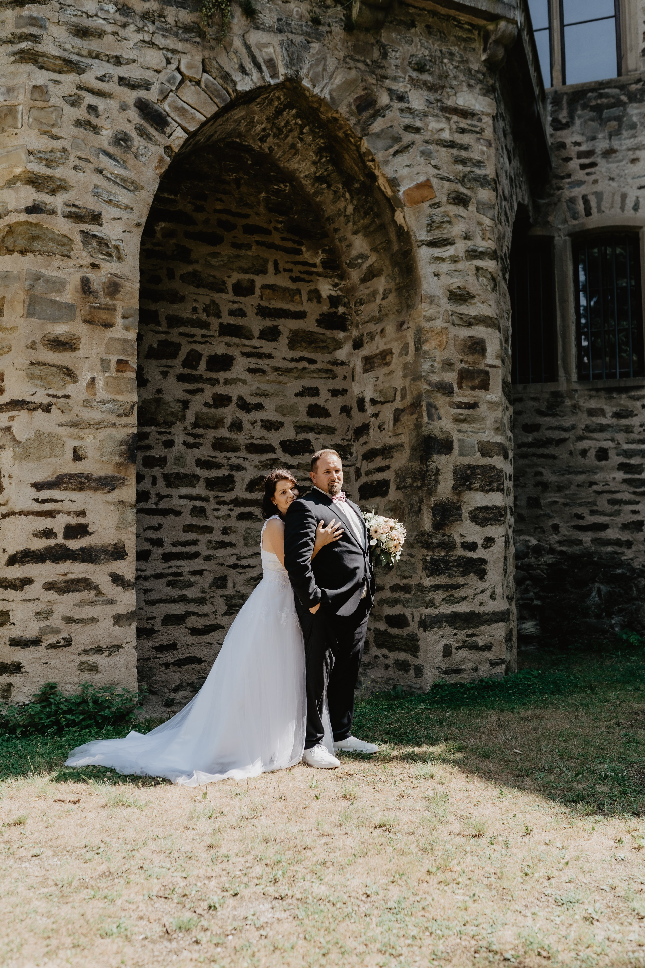 Zärtliche Umarmung der Braut, die ihren Bräutigam liebevoll an sich zieht.