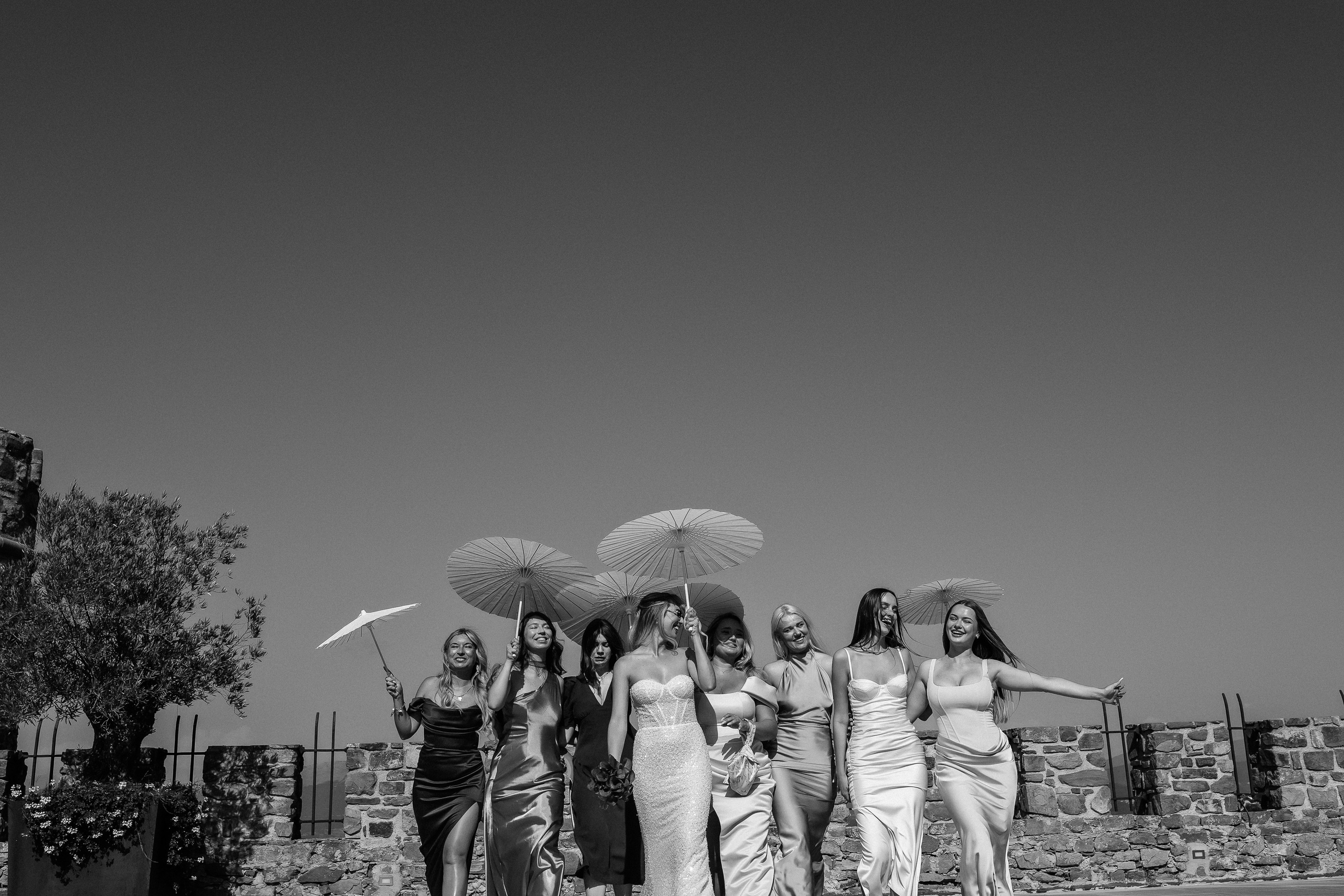 Bridesmaids throwing their parasols in the air in black and white
