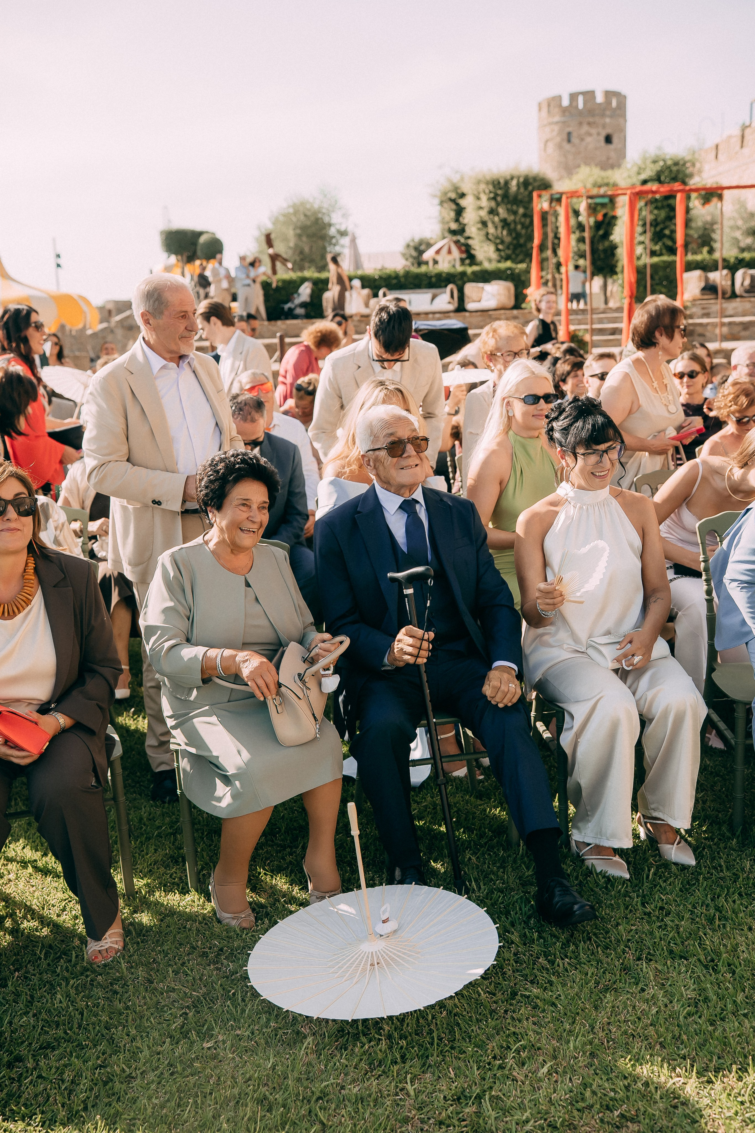 Guests laughing and fanning themselves during the outdoor ceremony