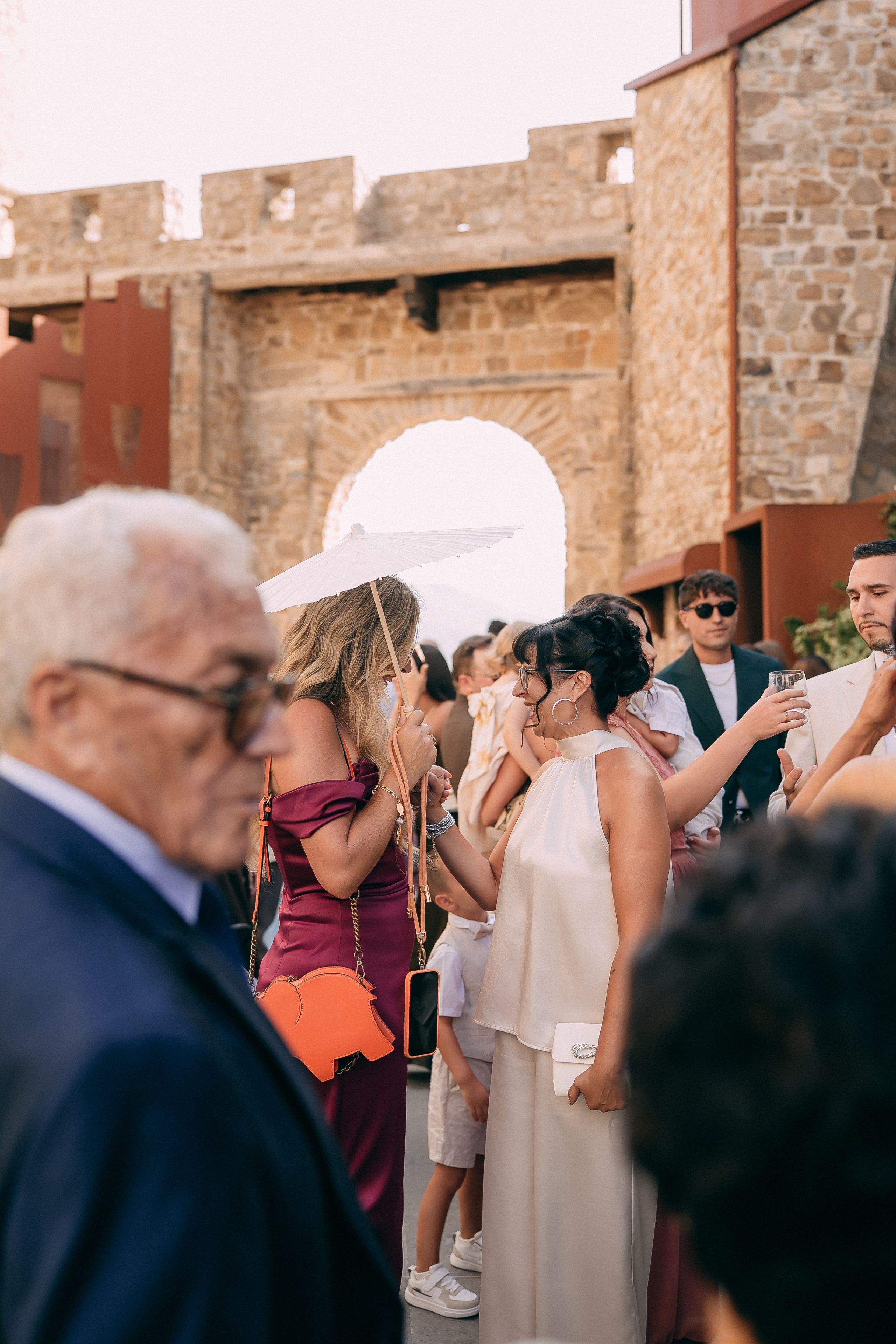 Guests with parasols gathering under the castle gate before the ceremony