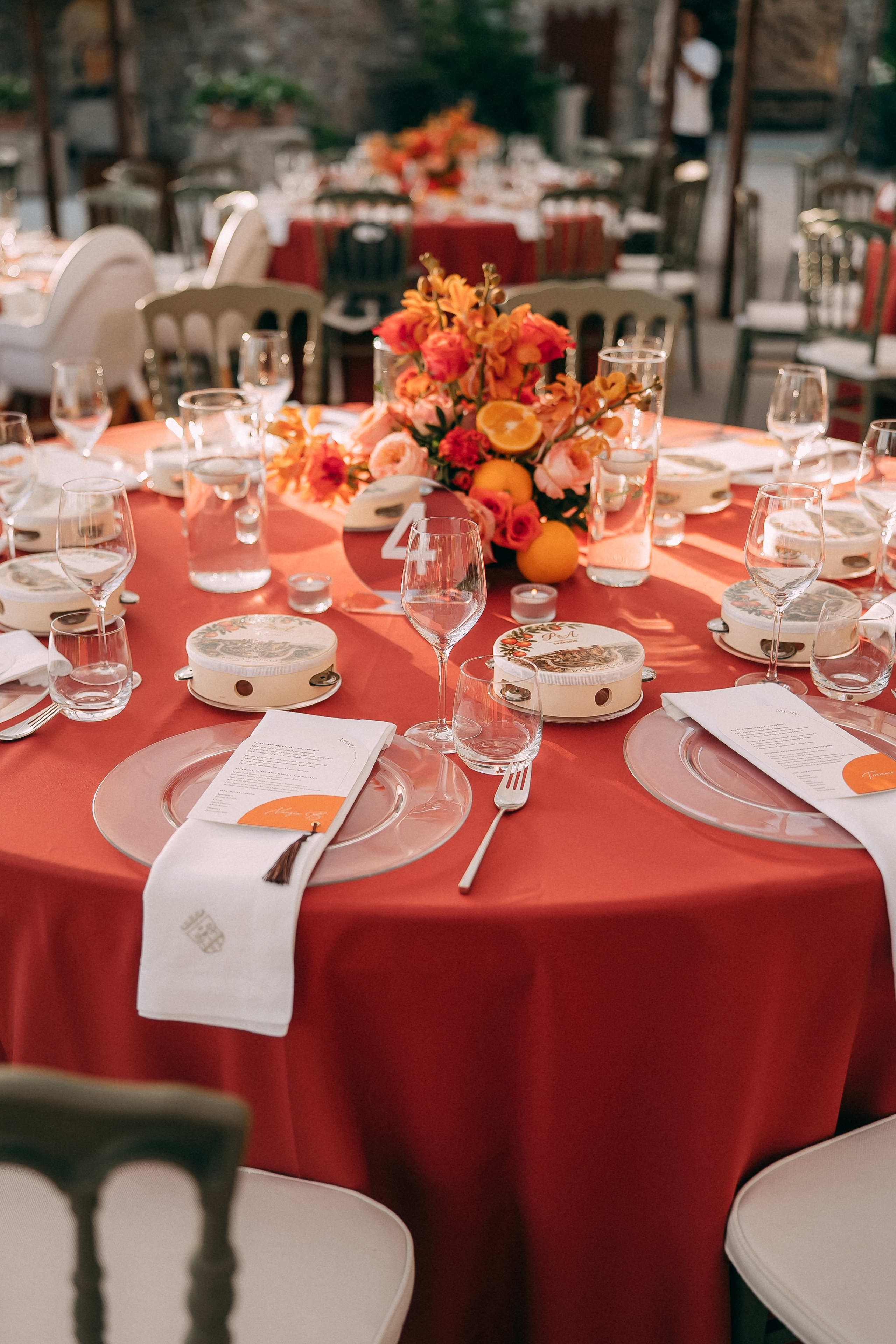 Wedding reception tables decorated in red, orange and citrus tones