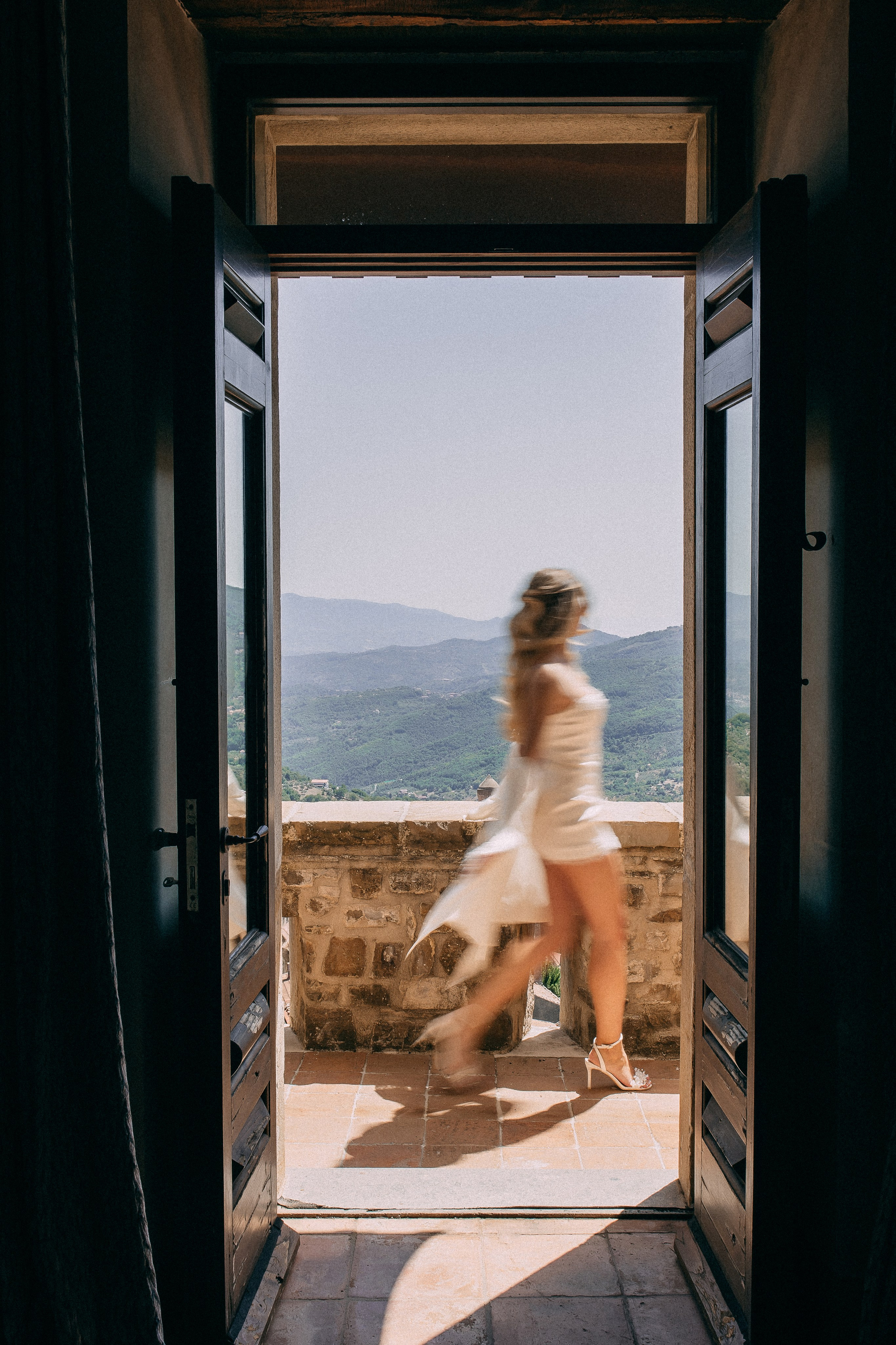 Bride walking through the castle doorway onto the sunlit terrace