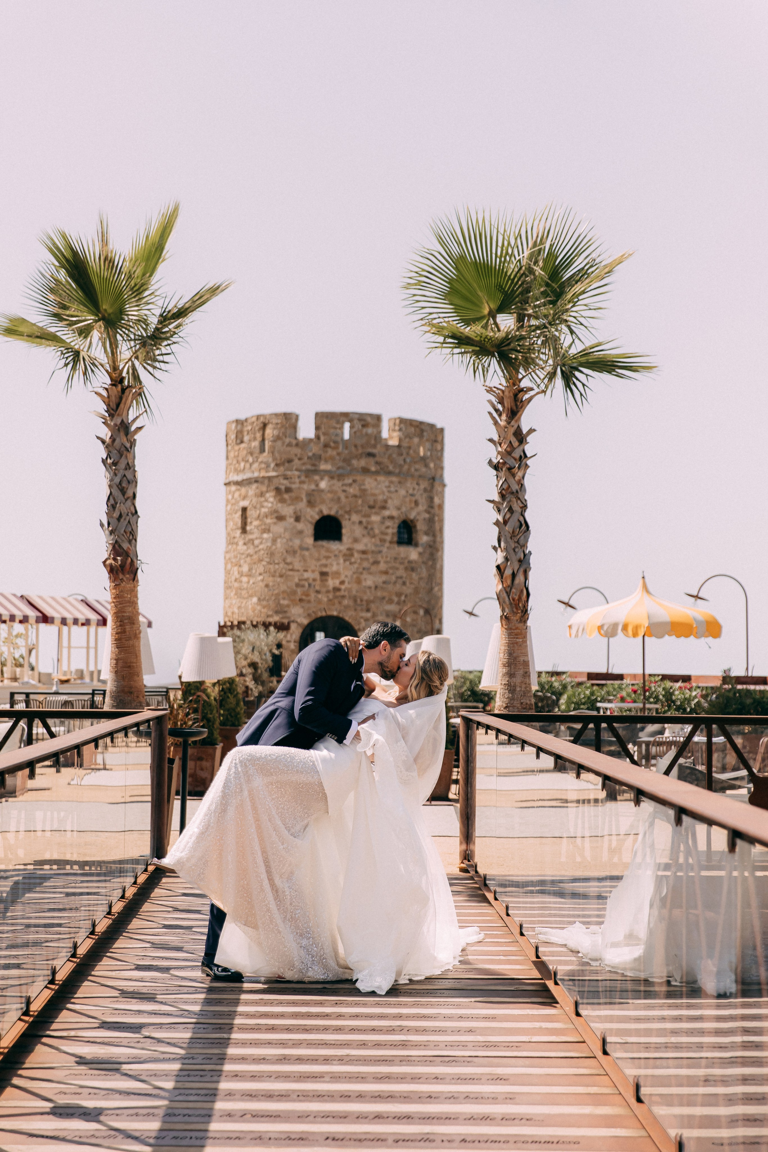 Bride and groom kissing on the wooden bridge between the palm trees