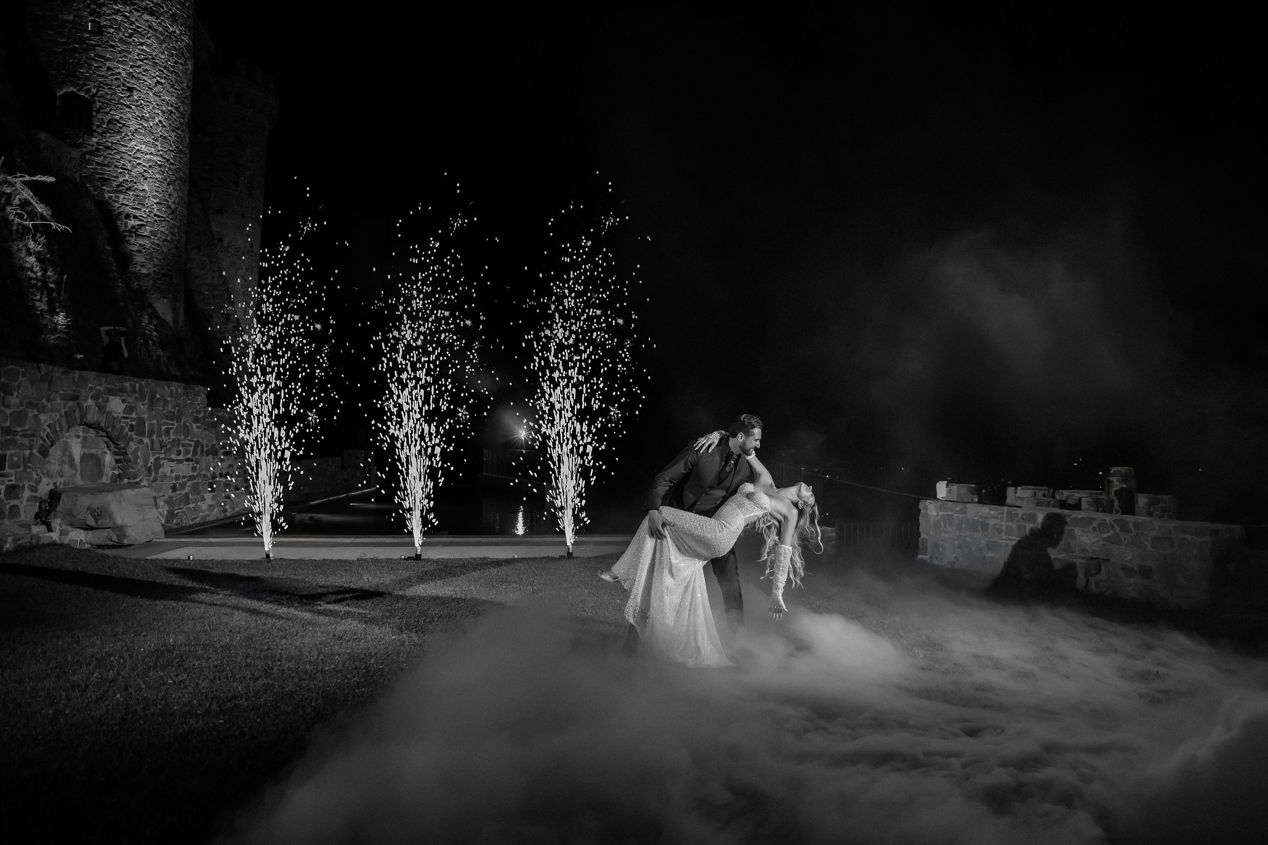 Newlyweds dancing surrounded by sparkler fountains at night