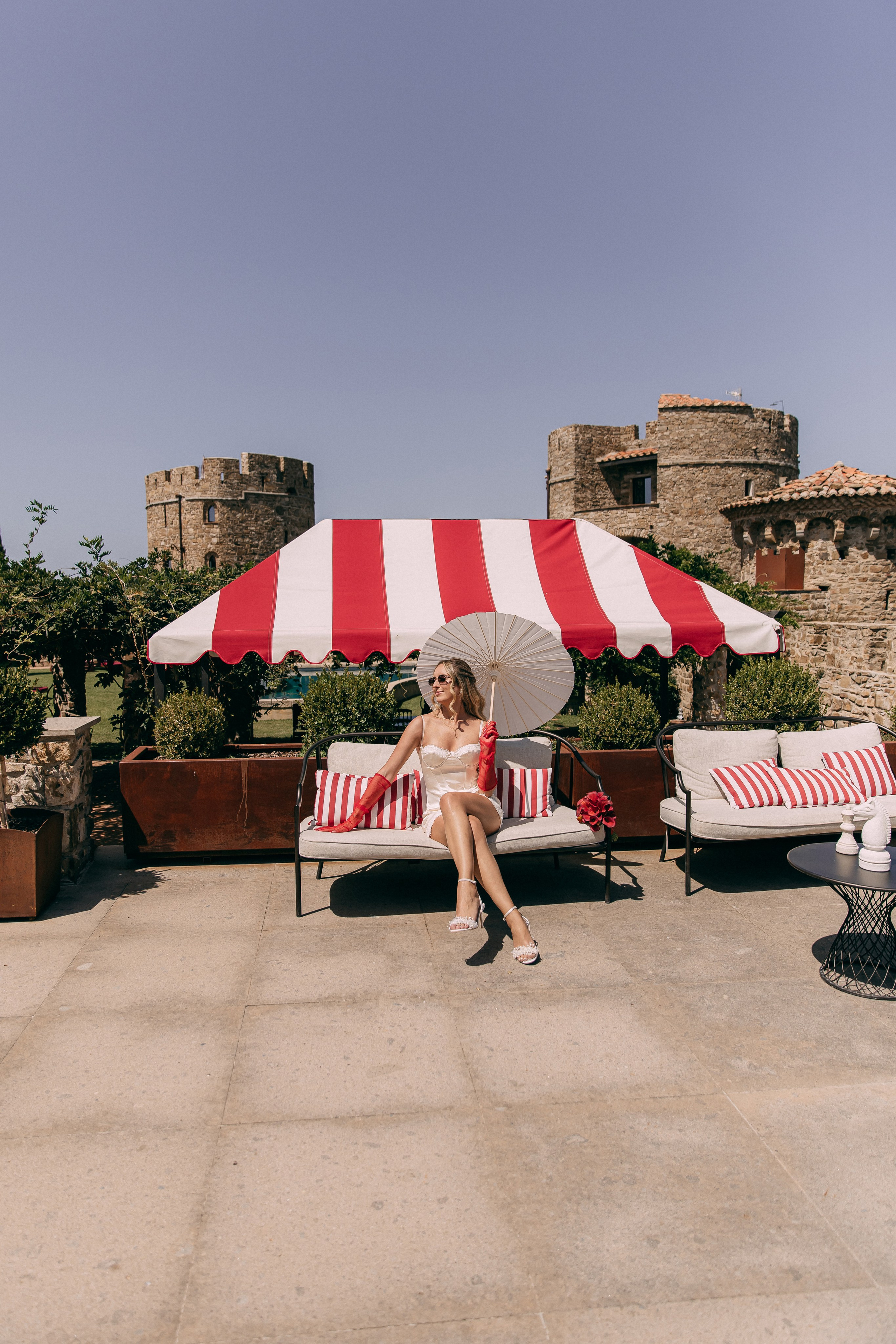 Wide view of the pool terrace with red striped umbrellas at the castle