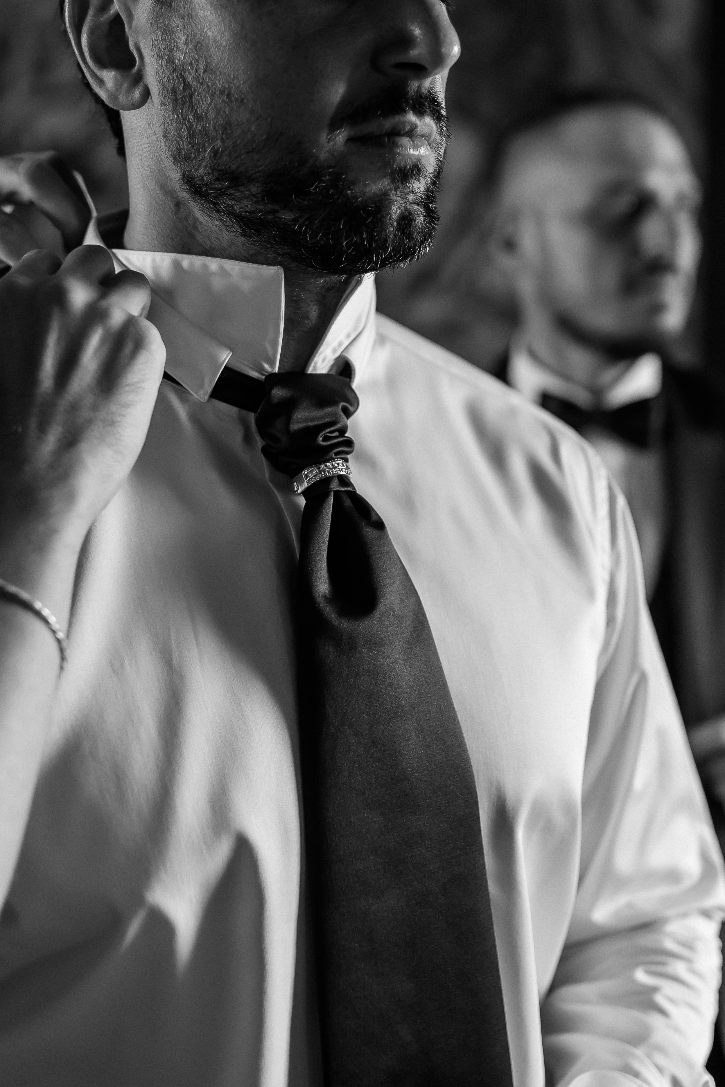 Close-up of the groom fastening his bow tie while getting ready for the wedding