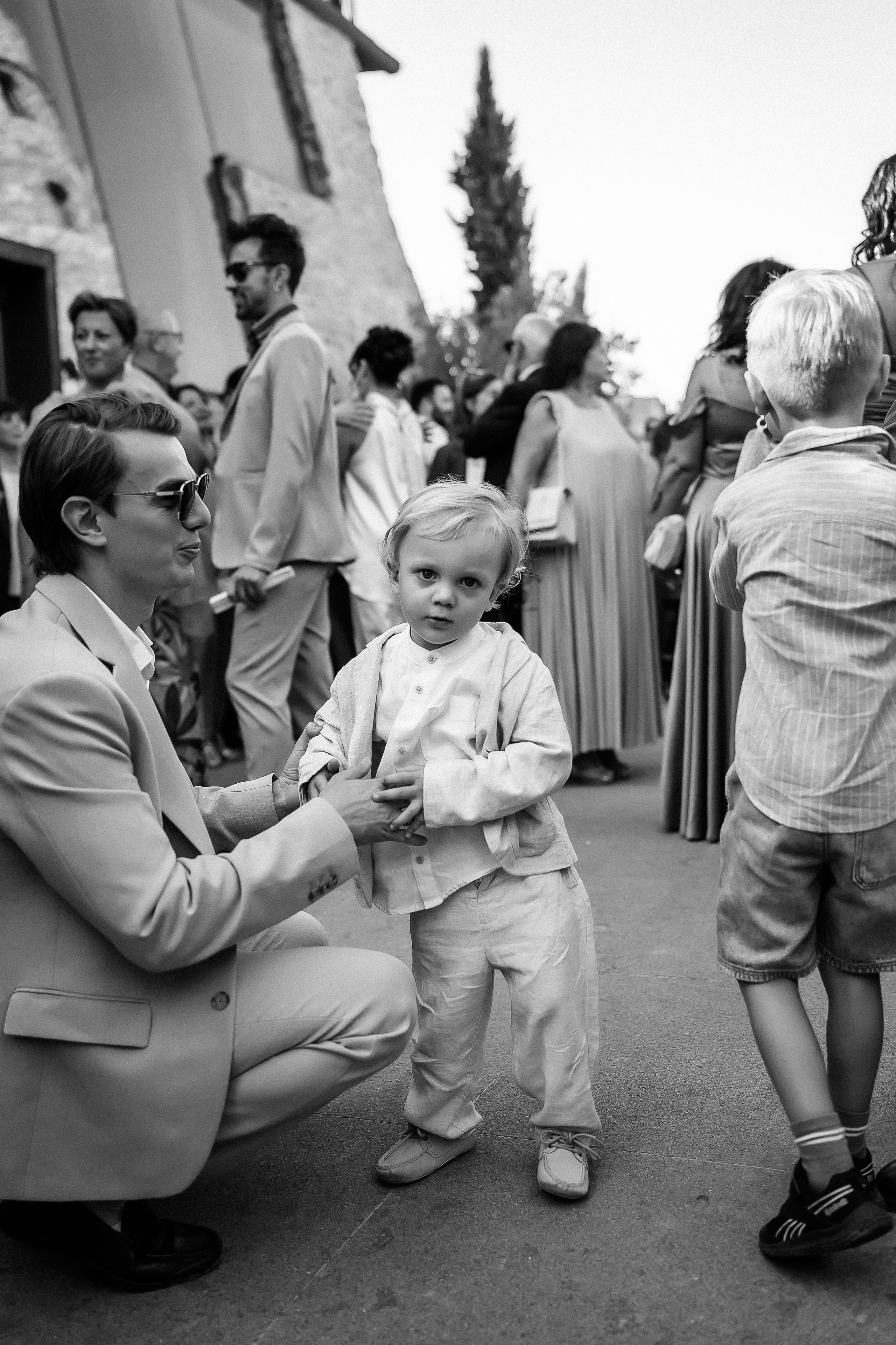Guest playing with a little boy before the ceremony, in black and white