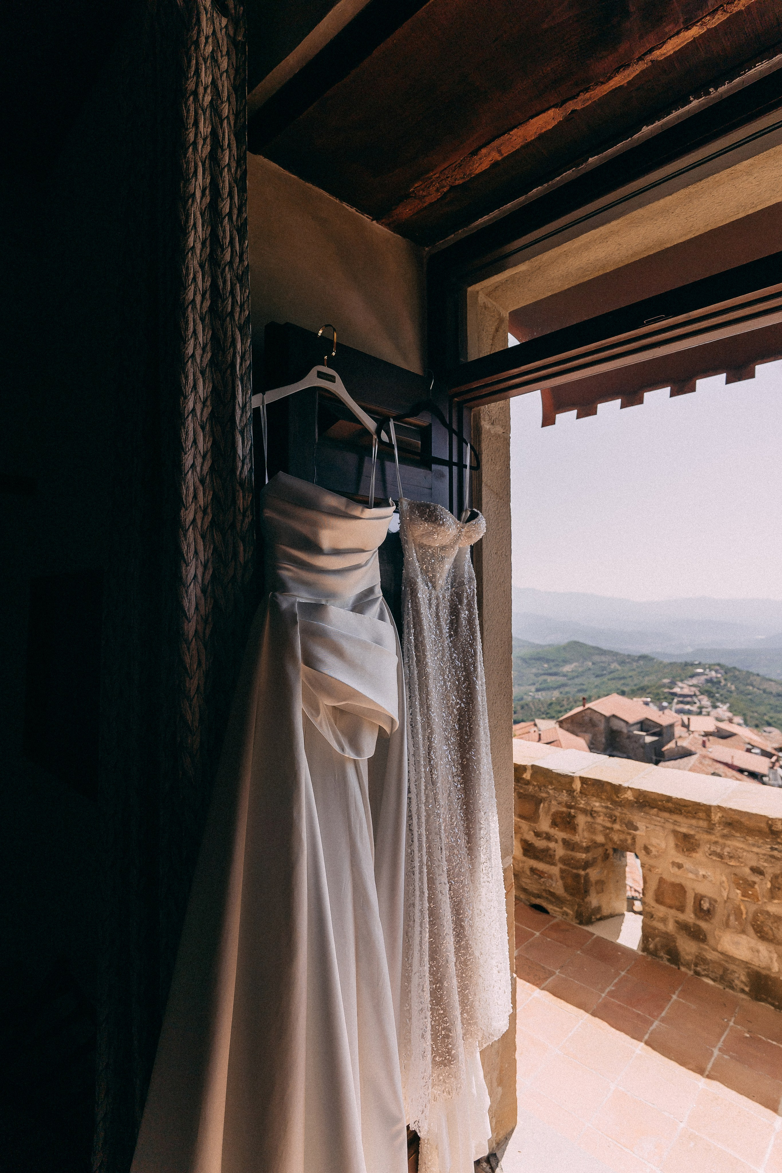 Bride's wedding dress hanging in a stone doorway with mountain views at Rocca Cilento castle