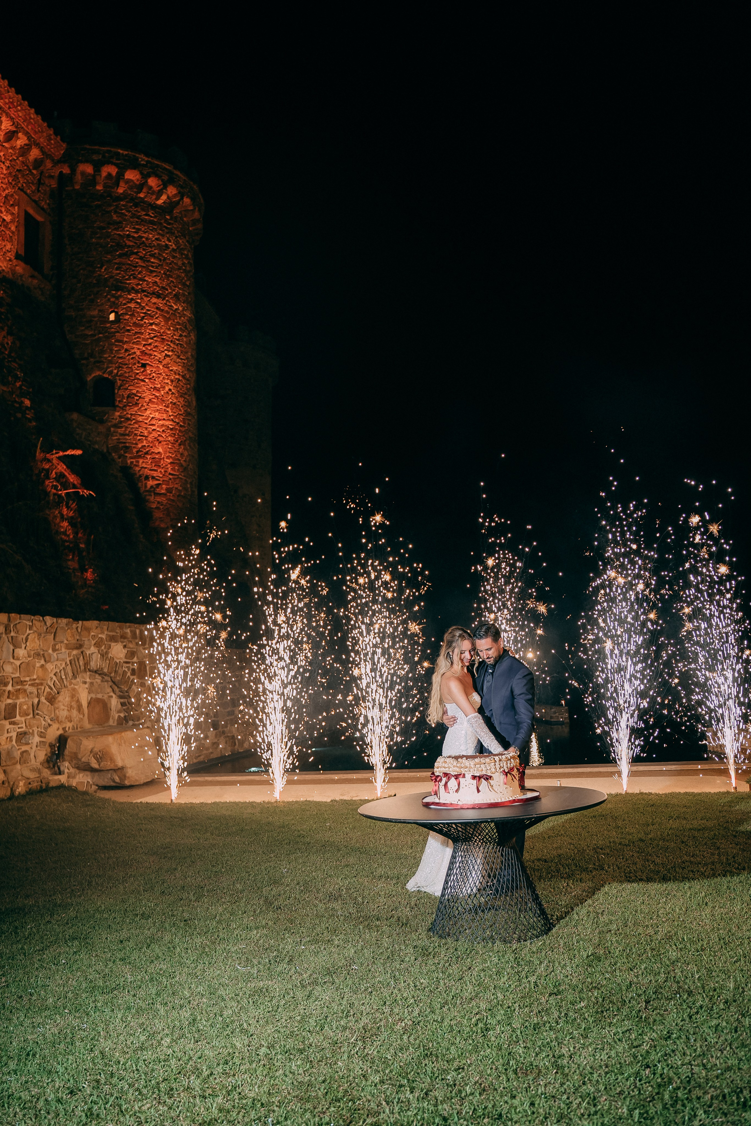 Wedding cake and sparkler fountains in front of the illuminated castle
