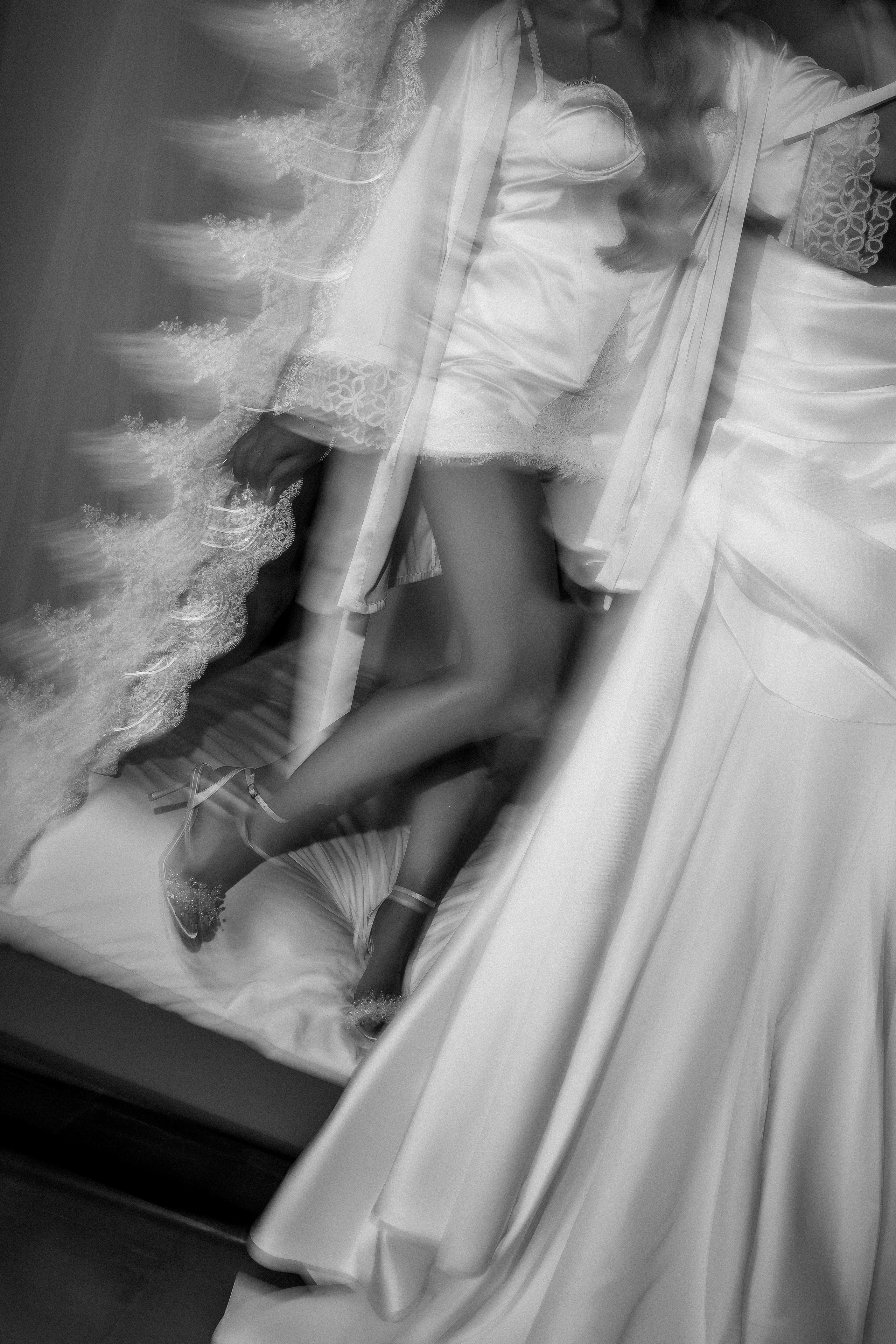 Black and white detail of the bride putting on her wedding shoes