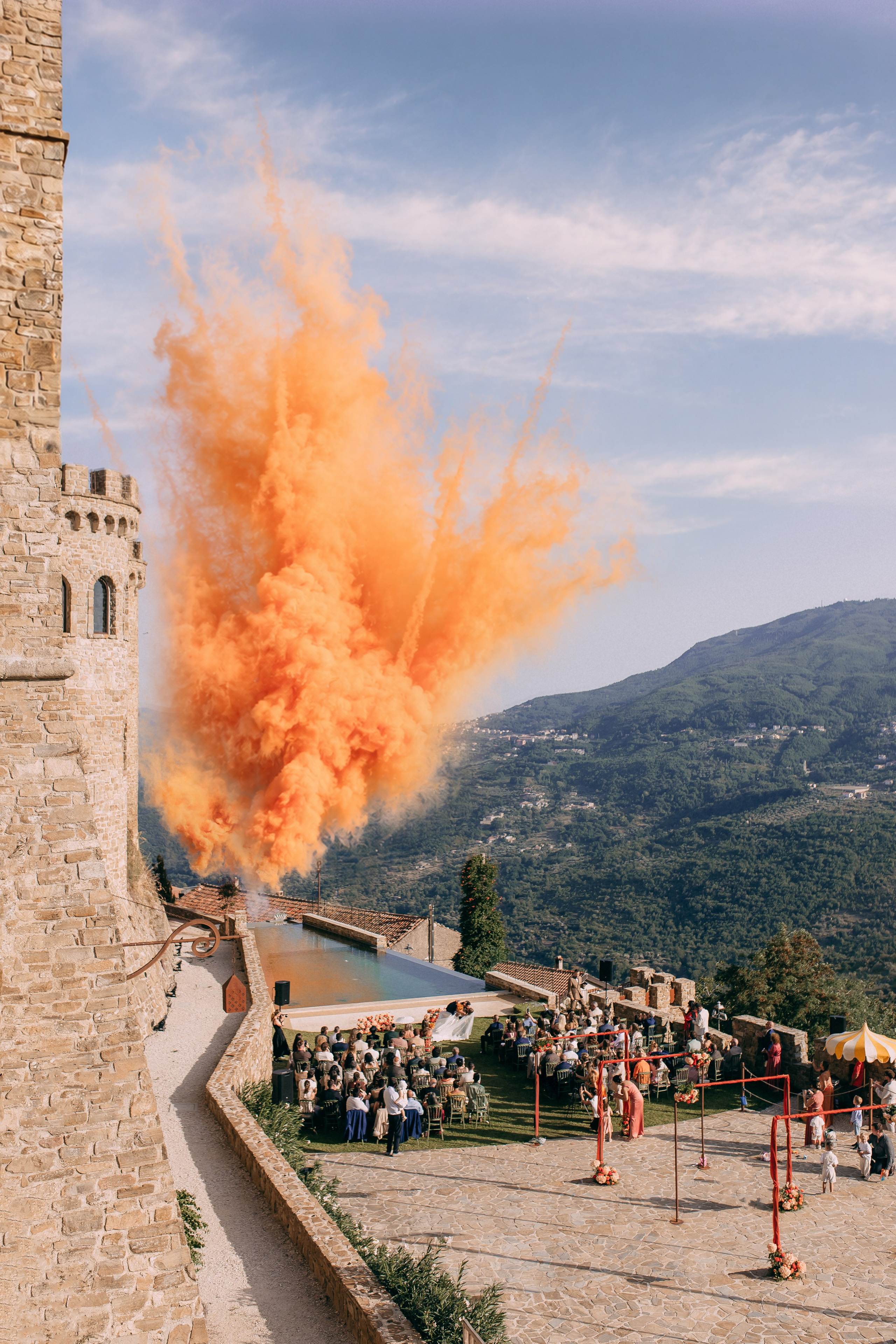 Orange smoke over the castle and mountains after the wedding ceremony