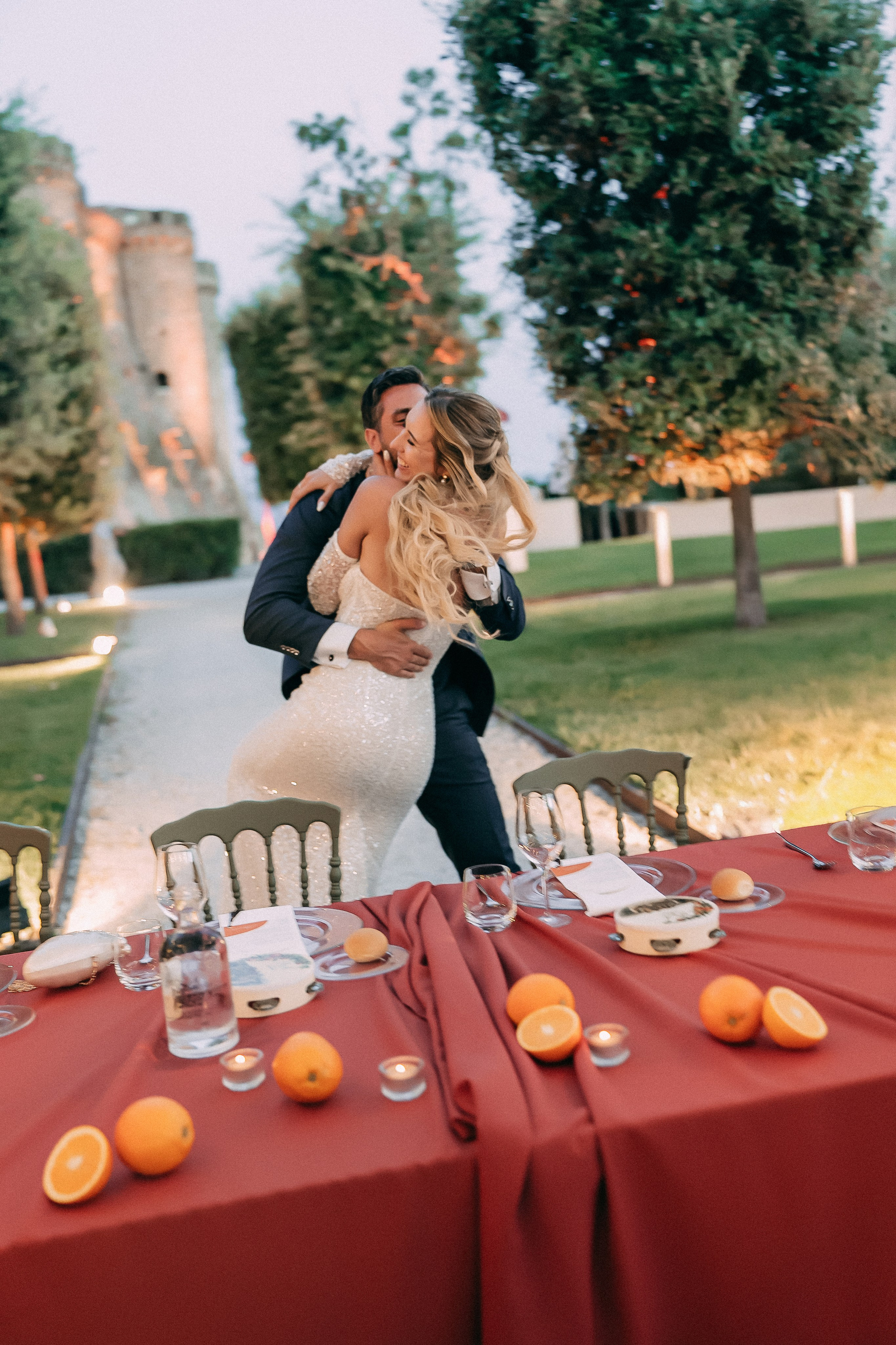 Groom lifting the bride at the reception table in the castle garden