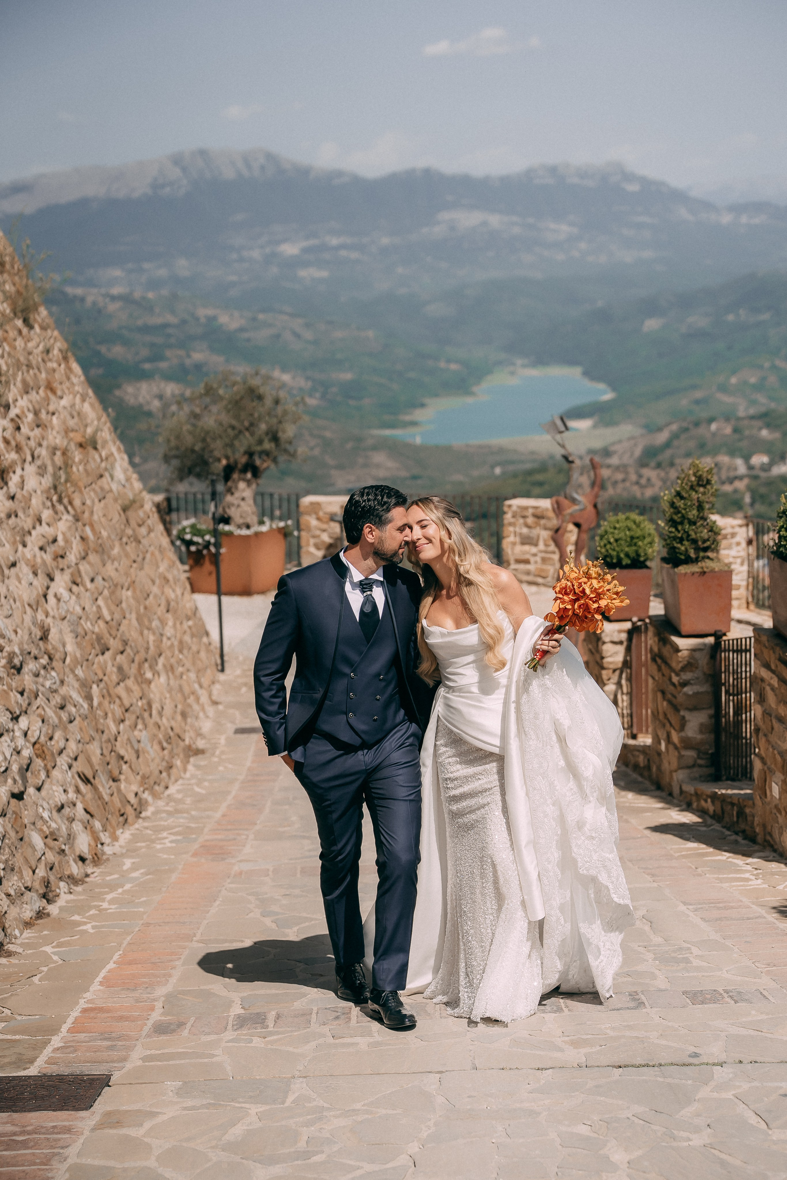 Bride and groom walking together along the castle wall in Cilento