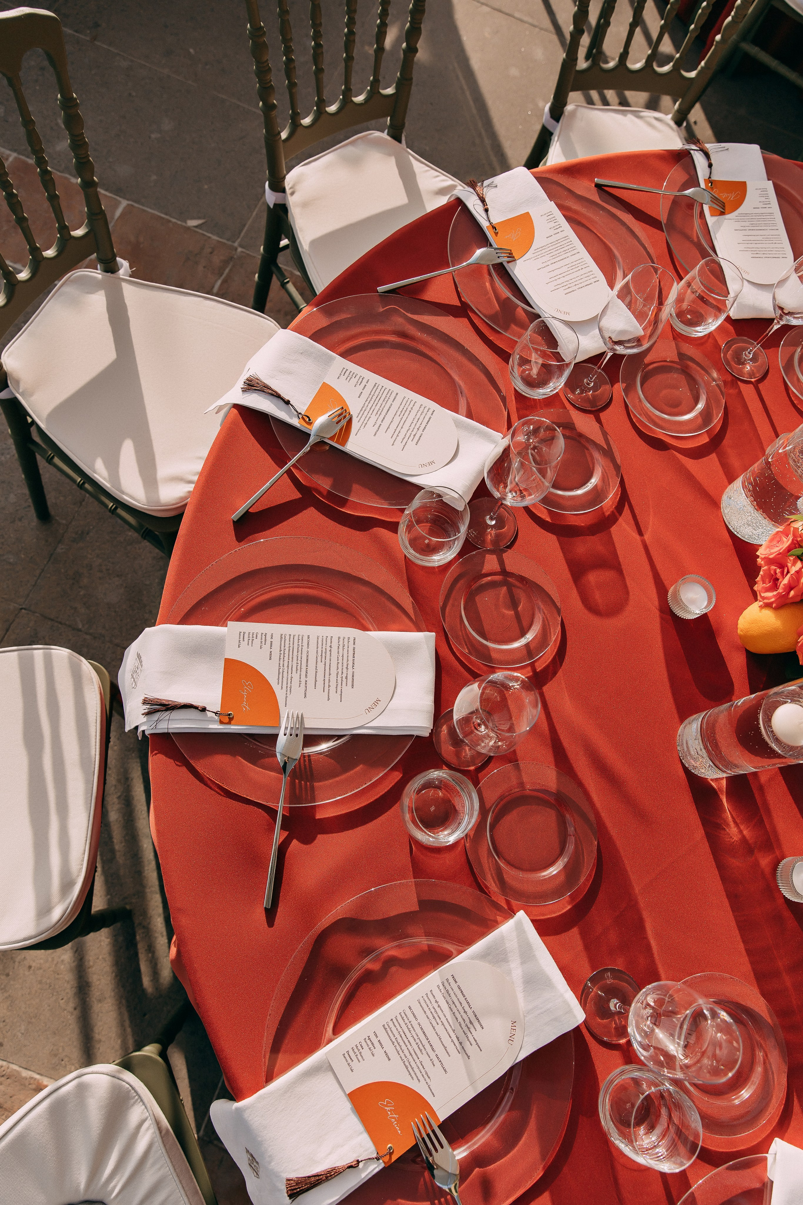 Red tablecloth with menus, glasses and oranges at the wedding reception