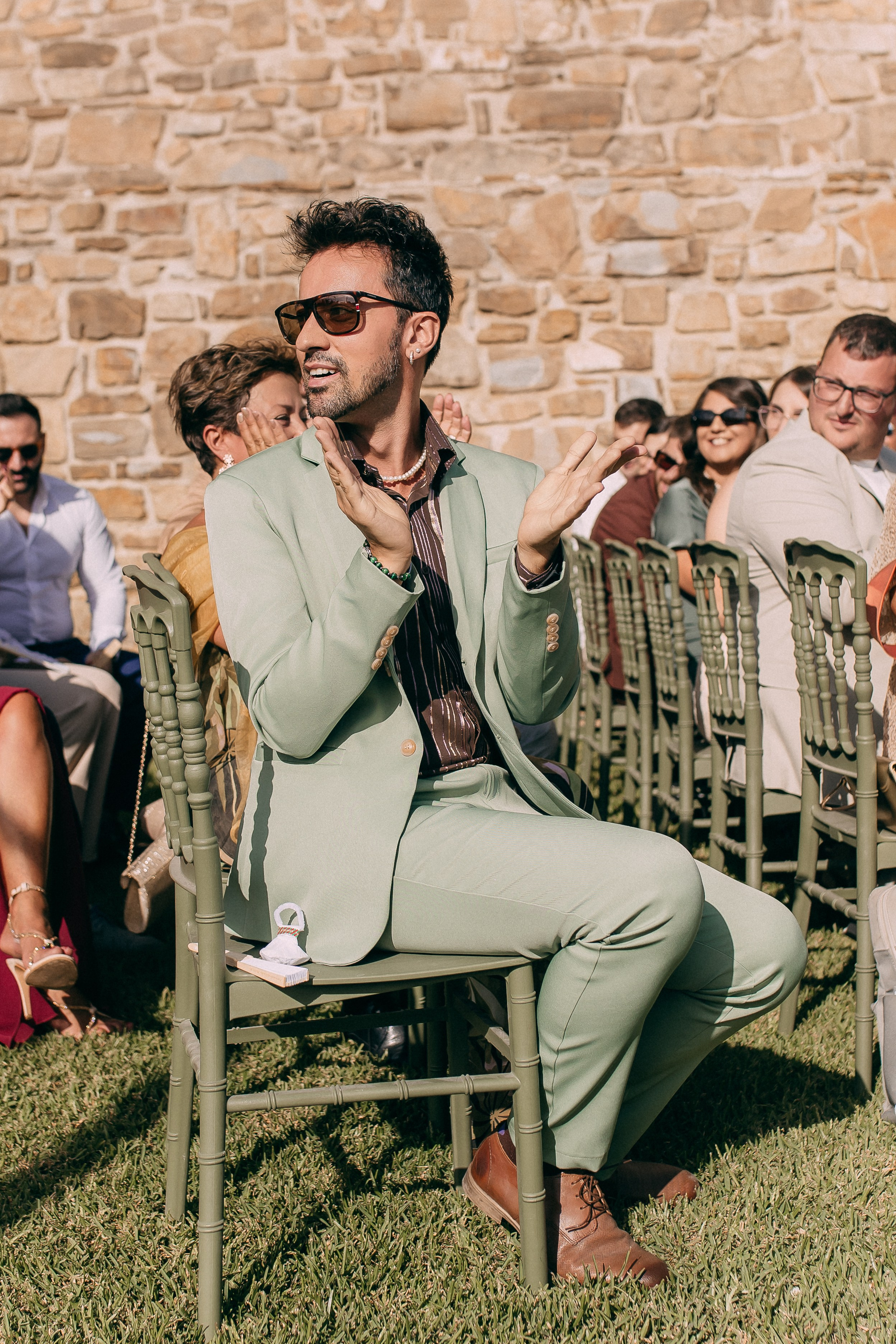 Guest in a sage green suit watching the ceremony at the castle