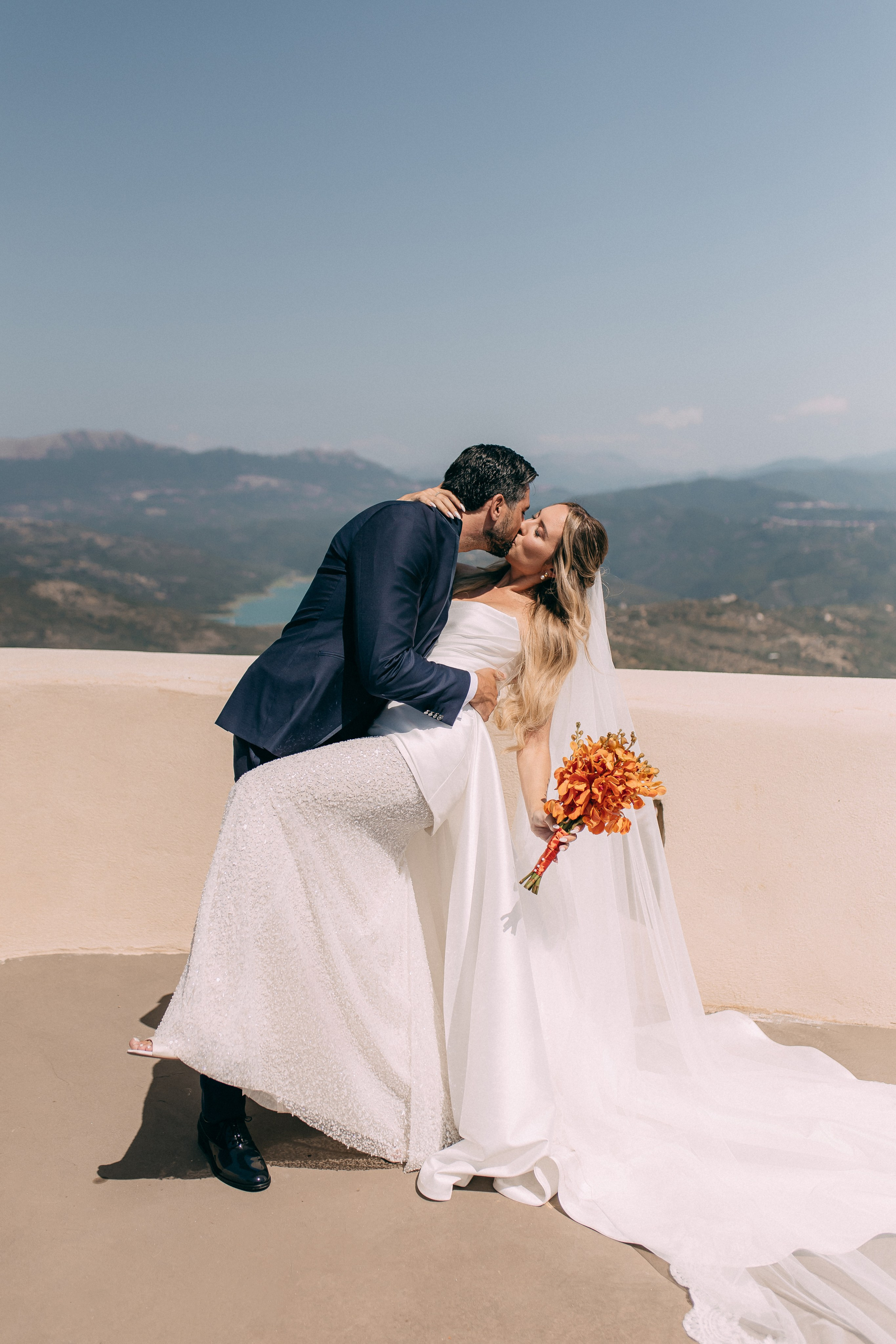 Bride and groom embracing on the terrace with an orange bridal bouquet