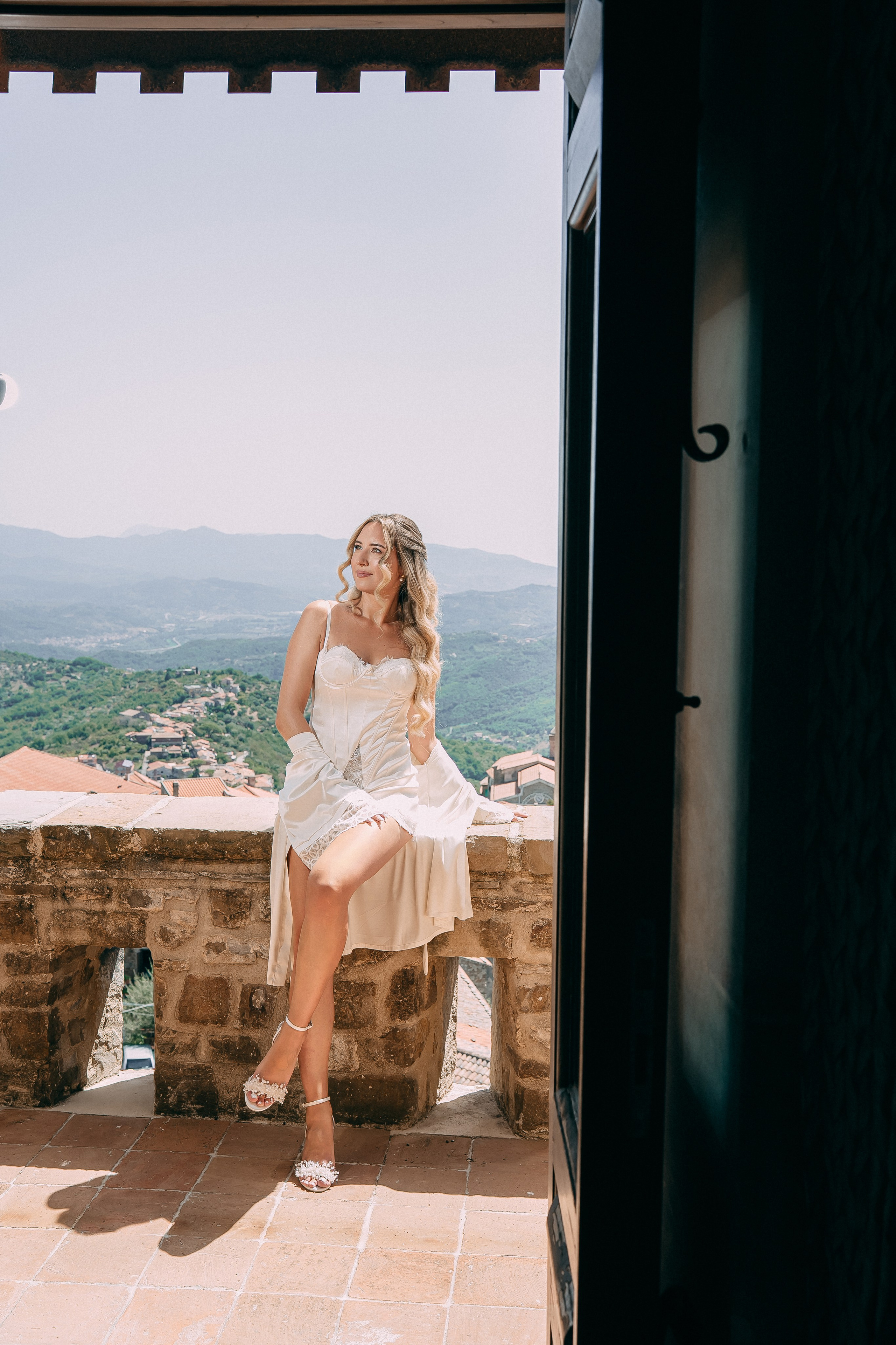 Bride sitting on the stone wall of the castle before the ceremony