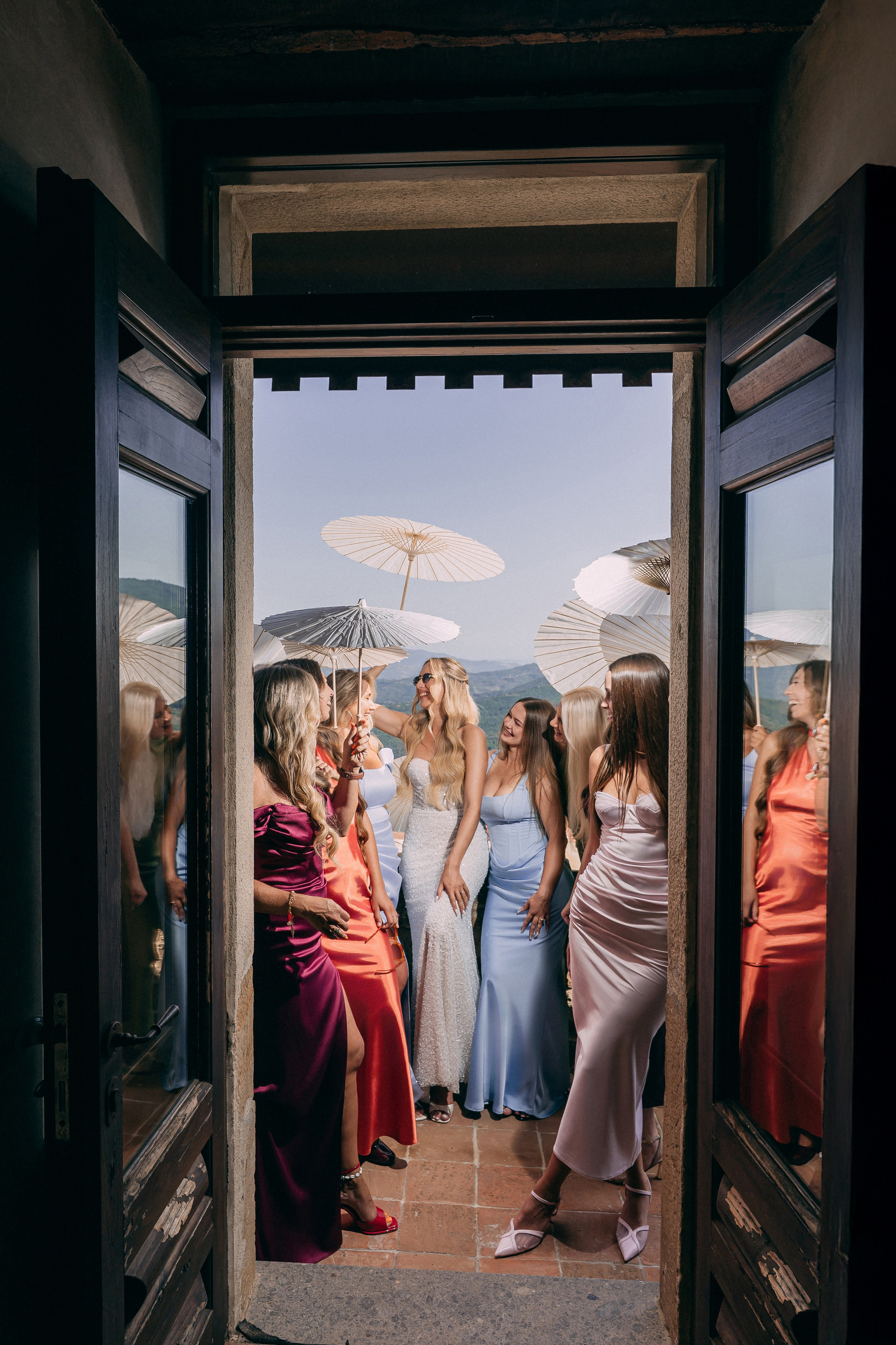 Bridesmaids in colourful dresses framed in the castle doorway