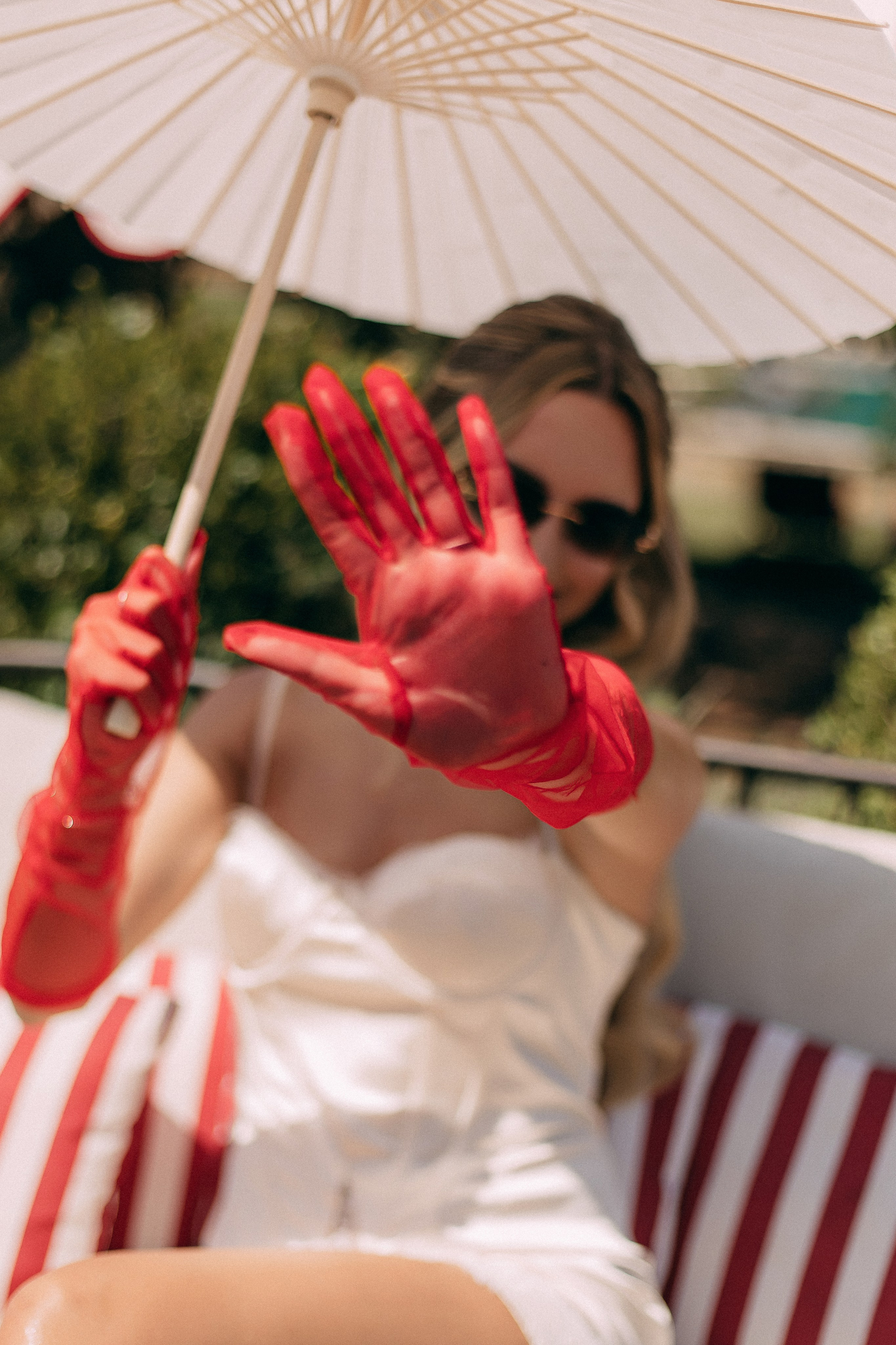 Bride in red gloves holding a paper parasol against the blue sky