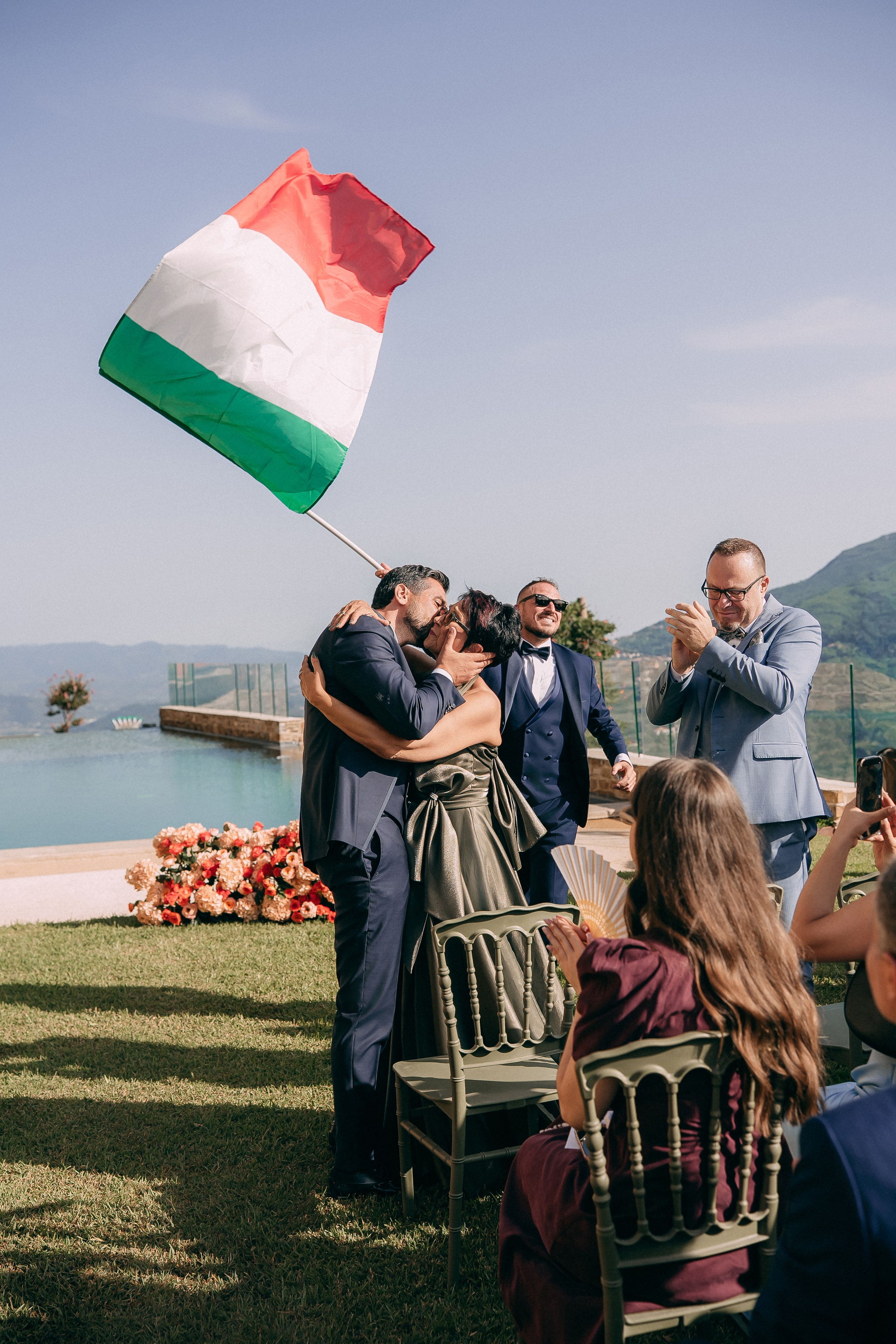 Groom greeting his guests as the Italian flag waves at the ceremony