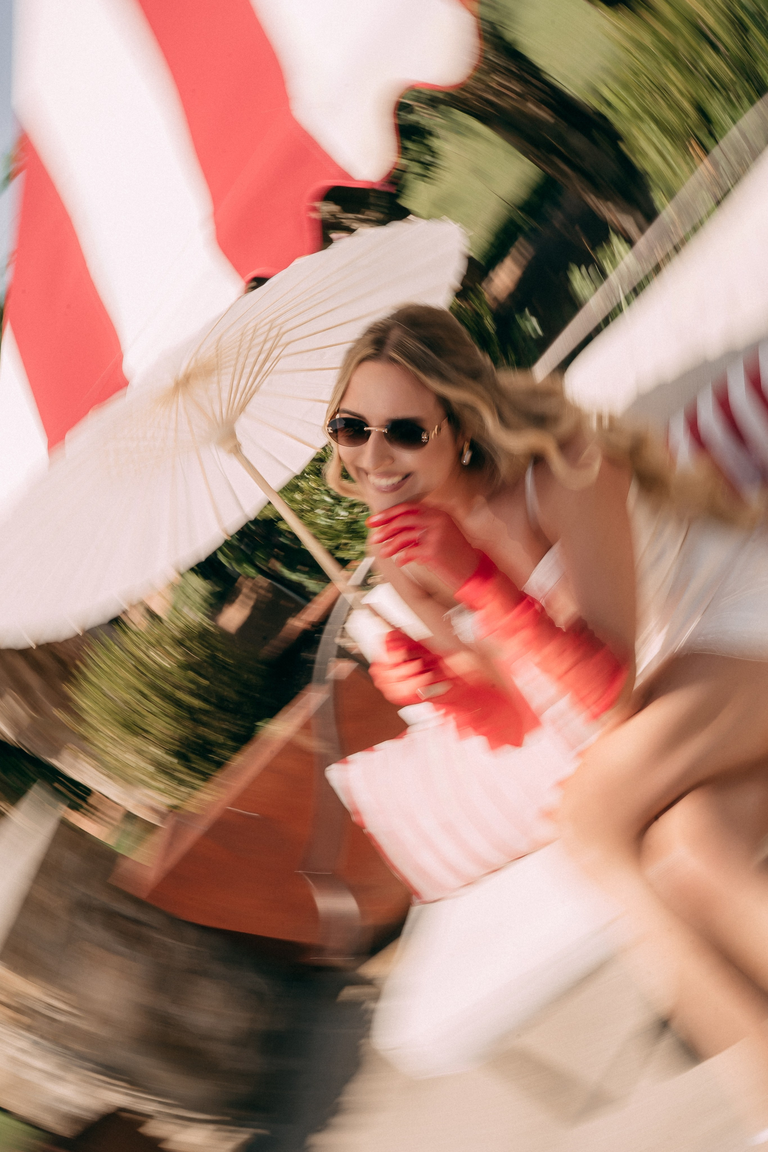 Playful blurred photo of the bride laughing under her paper parasol
