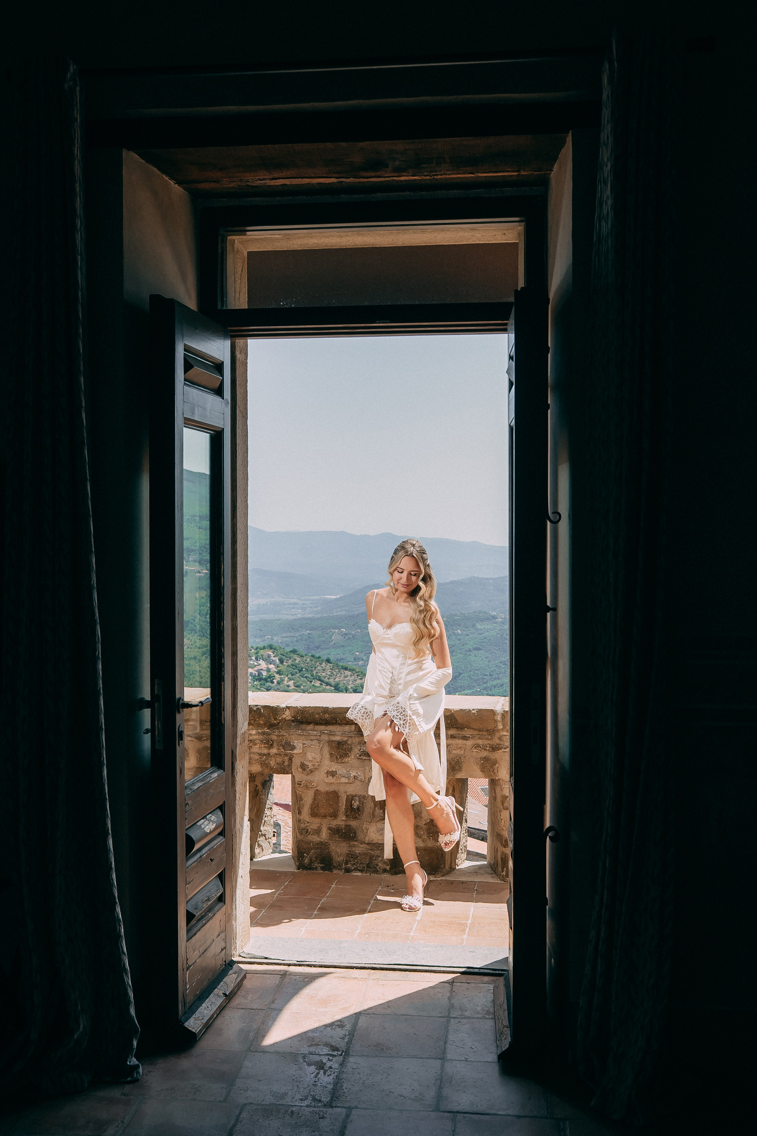 Bride framed in the doorway of the castle with a valley view behind