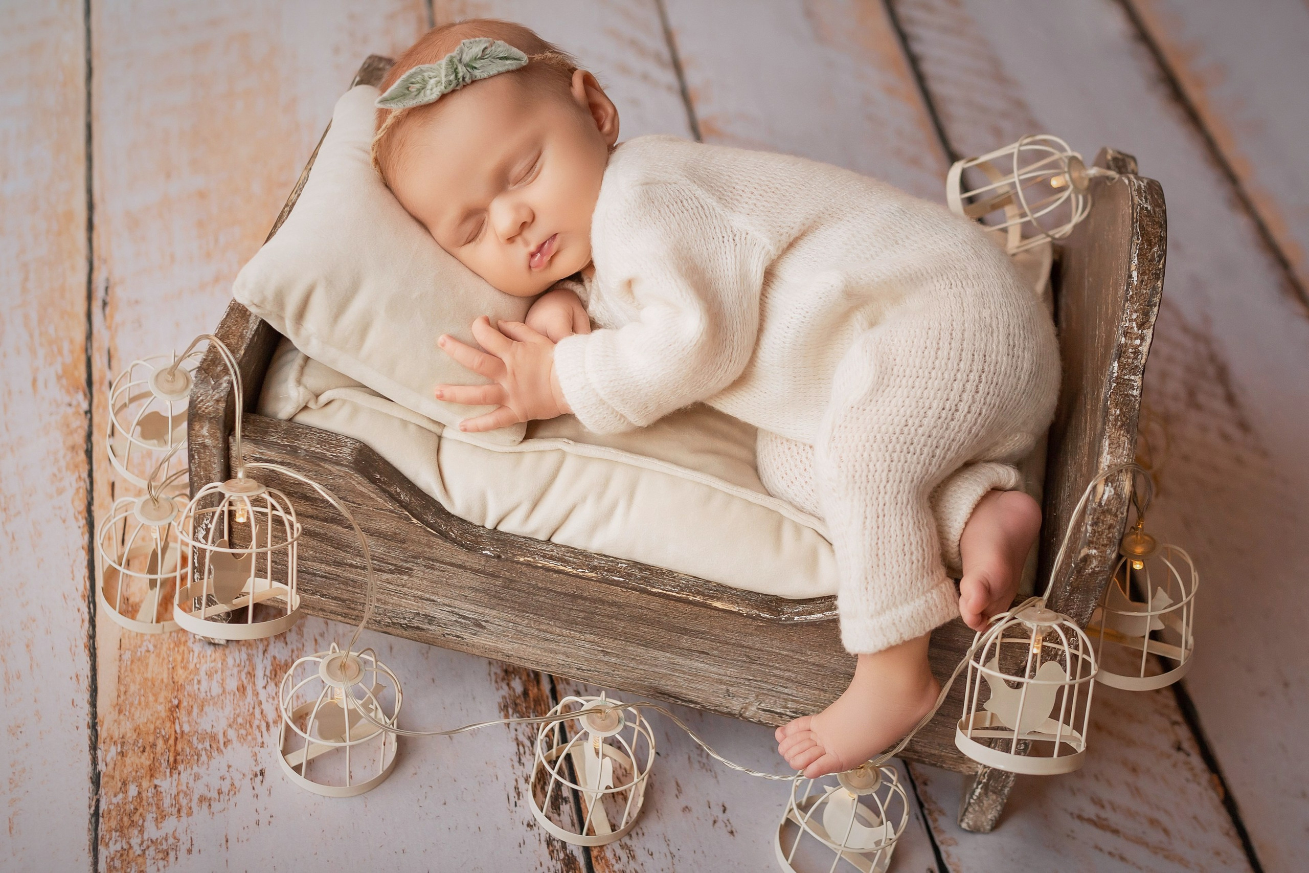 Newborn girl in wooden cradle surrounded by twinkling lanterns