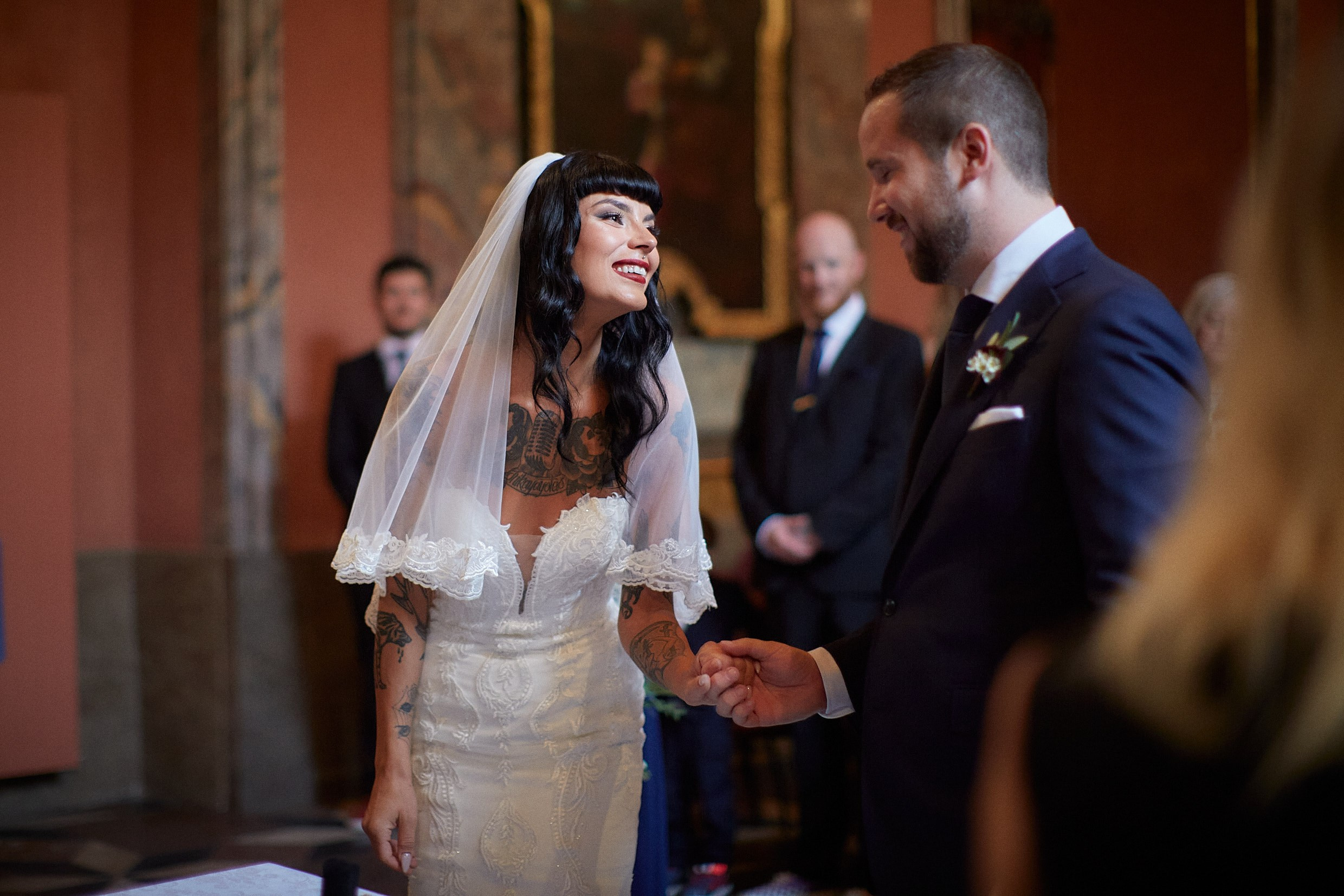 Bride smiling warmly grasping groom's hands during ceremony.