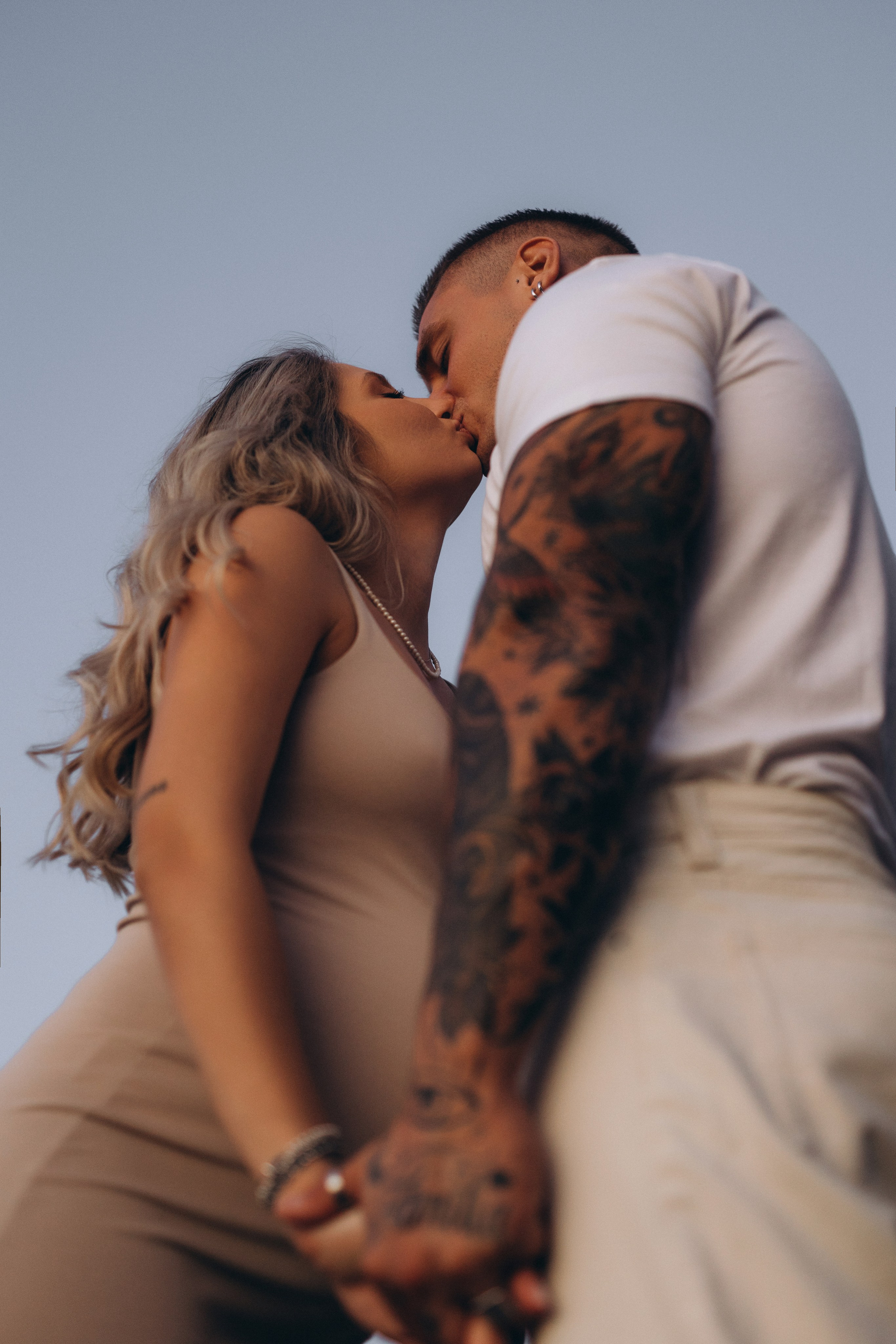 Ritratto maternity moderno di una coppia in attesa al mare durante la golden hour.