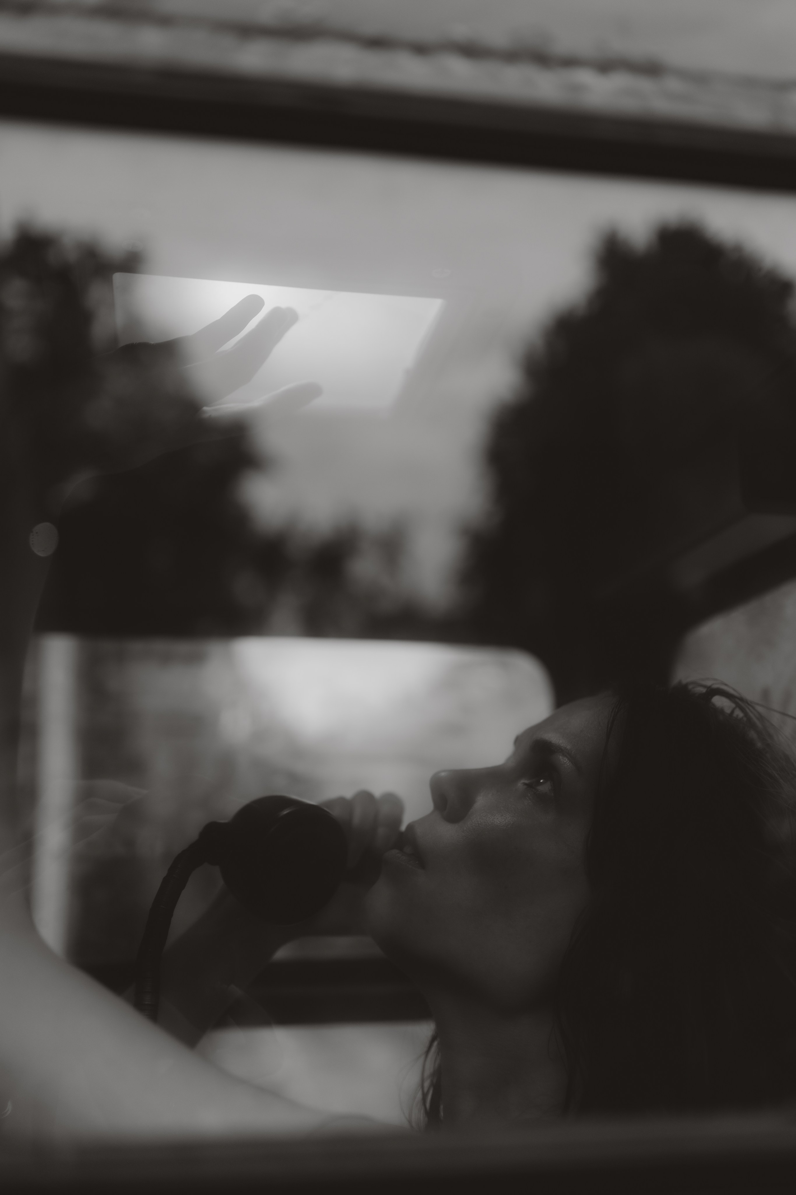 Fine art portrait of a woman inside a phone booth, looking up, cinematic mood