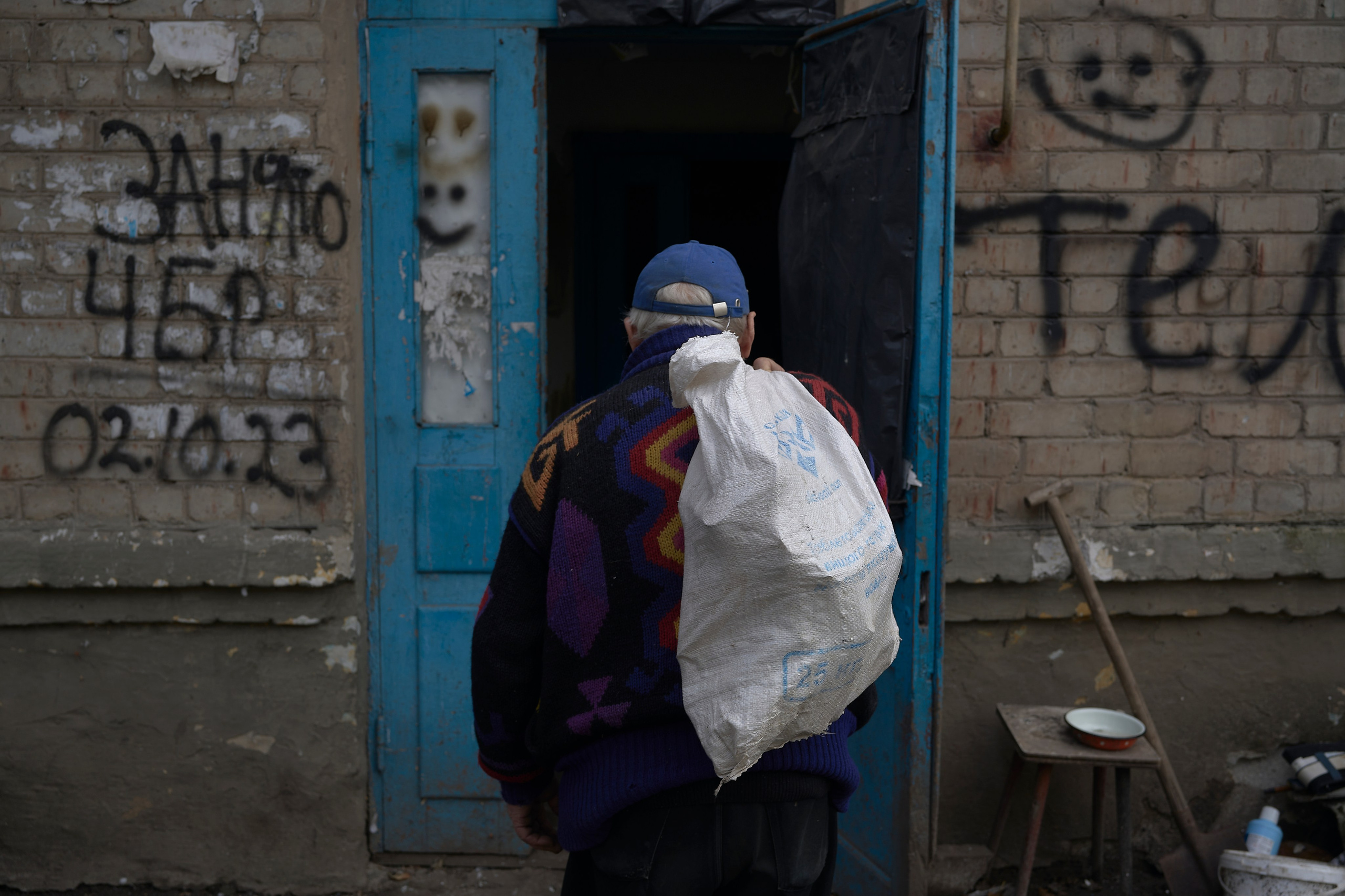 A local resident carries a sack with wood to heat the appartment. Since February 2023 town doesn't have water, gas and electricity supply. Chasiv Yar.
