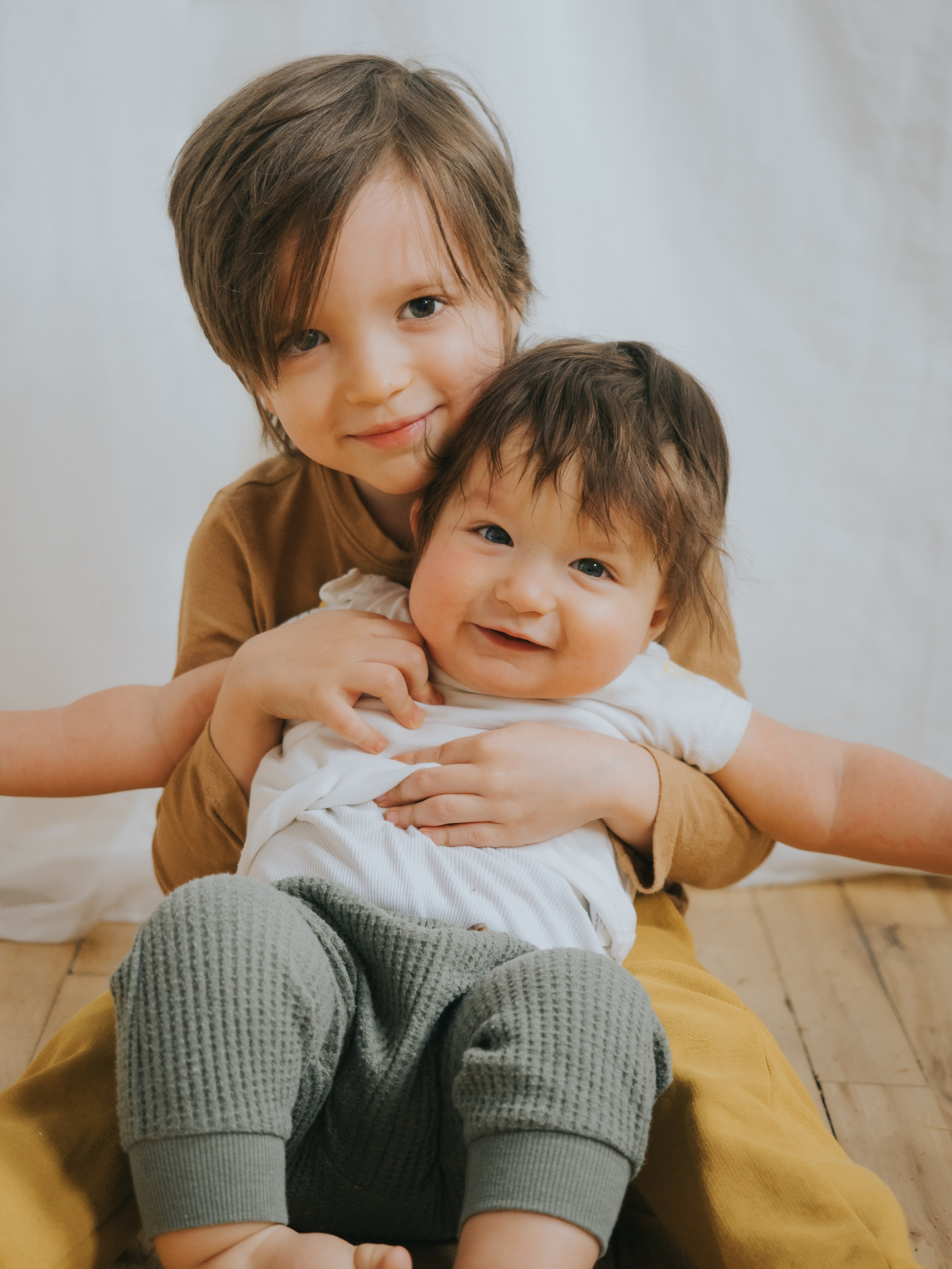Two young brothers hugging and looking in camera.