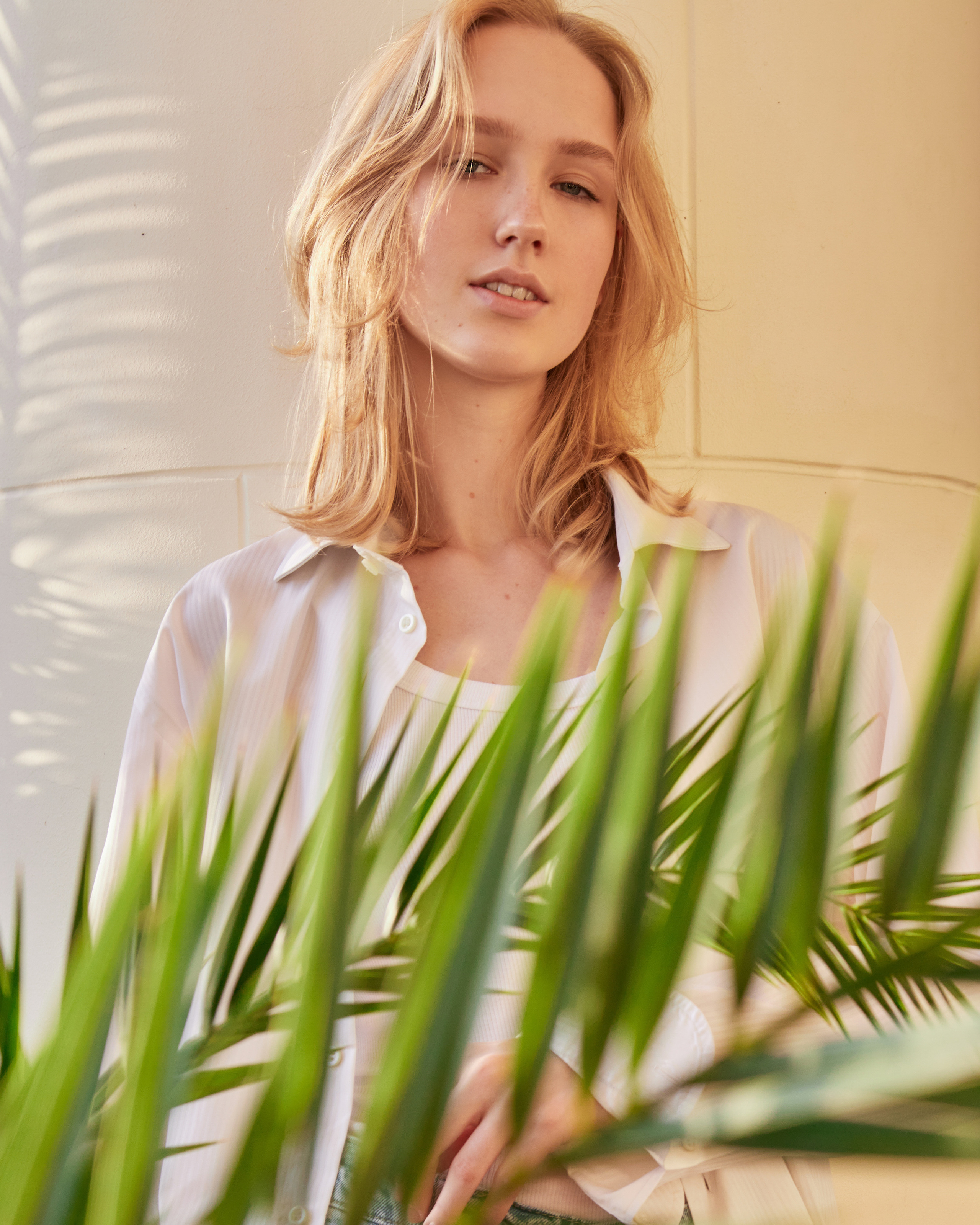 Retrato femenino artístico con luz suave y hojas tropicales