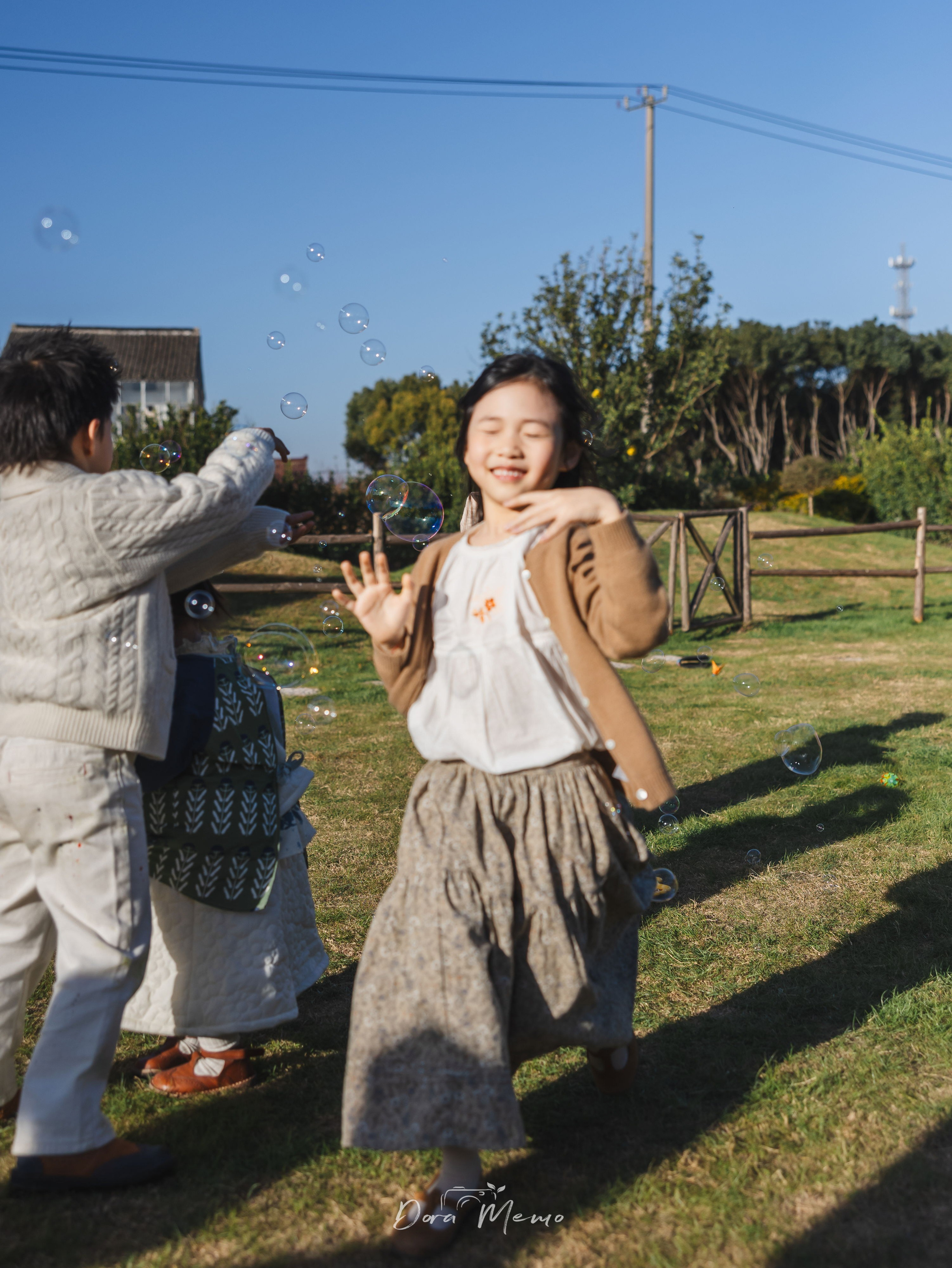 Shanghai family photographer - girl laughing with eyes closed, playing with bubbles at birthday celebration