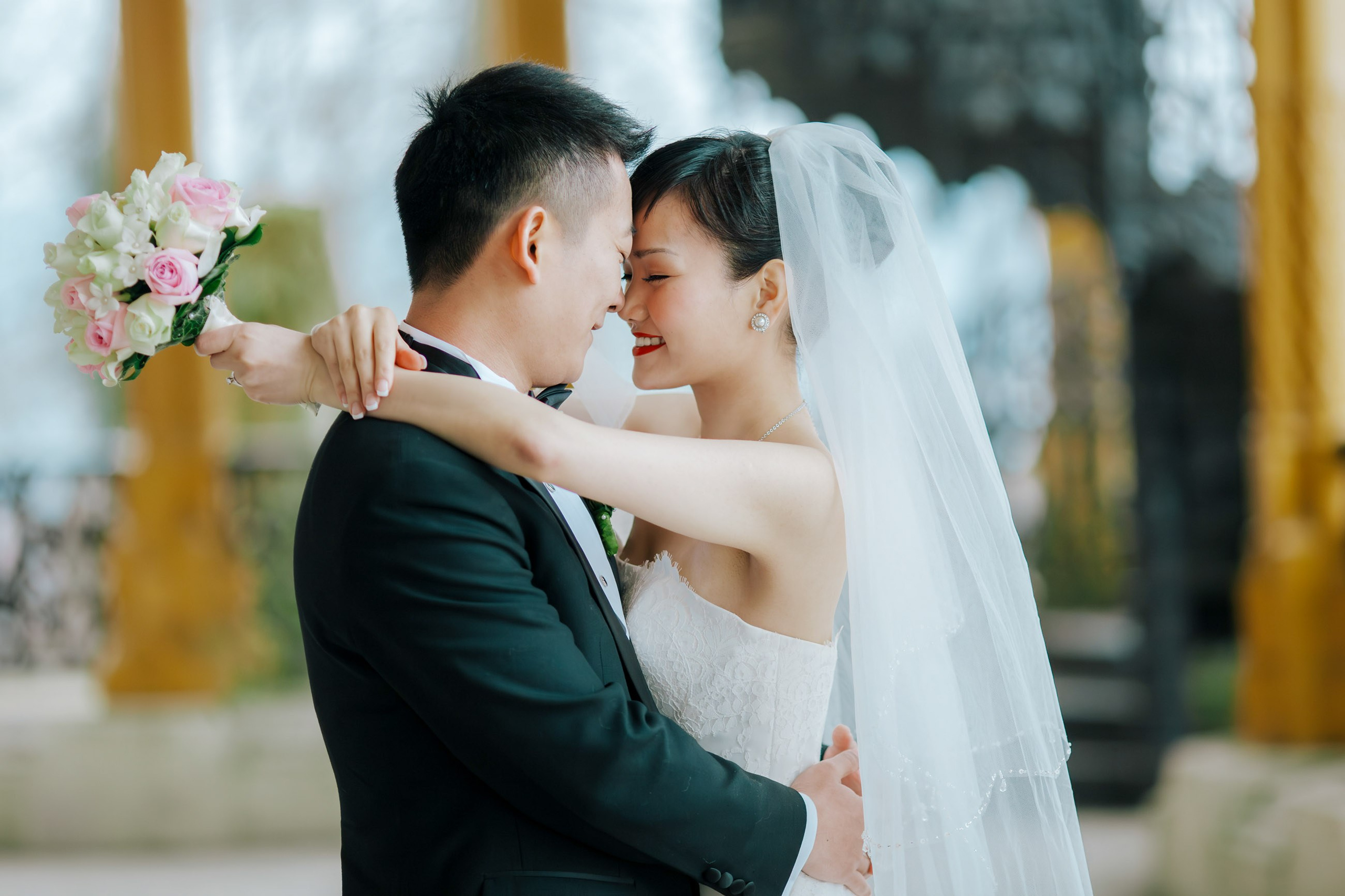 A beaming and radiant bride from Hong Kong throws her arms around her smiling groom on the historic grounds of the State Chateau of Hluboka during their destination wedding in Bohemia.