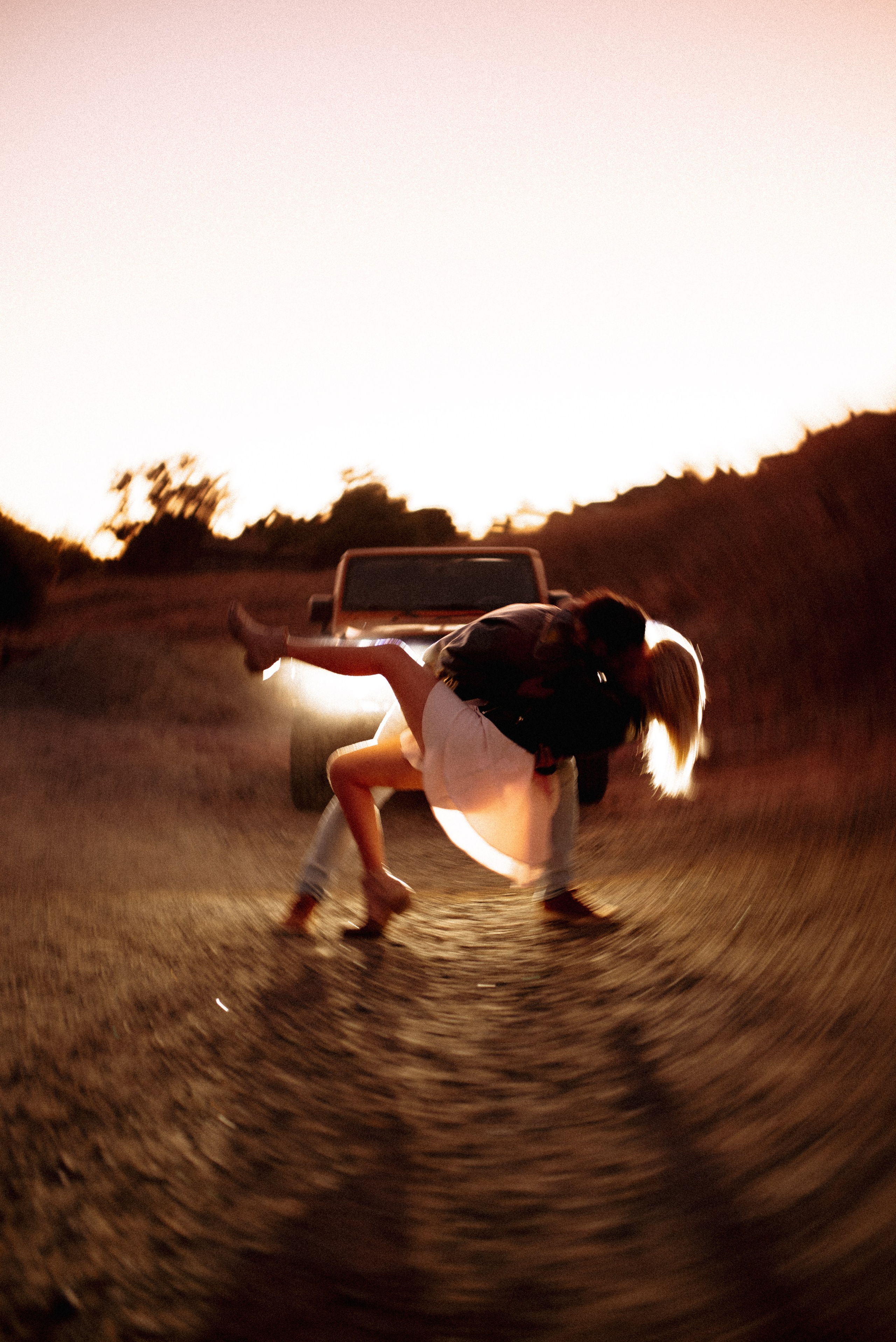 The couple sways gracefully in car headlights, sharing a beautiful, intimate dance moment.