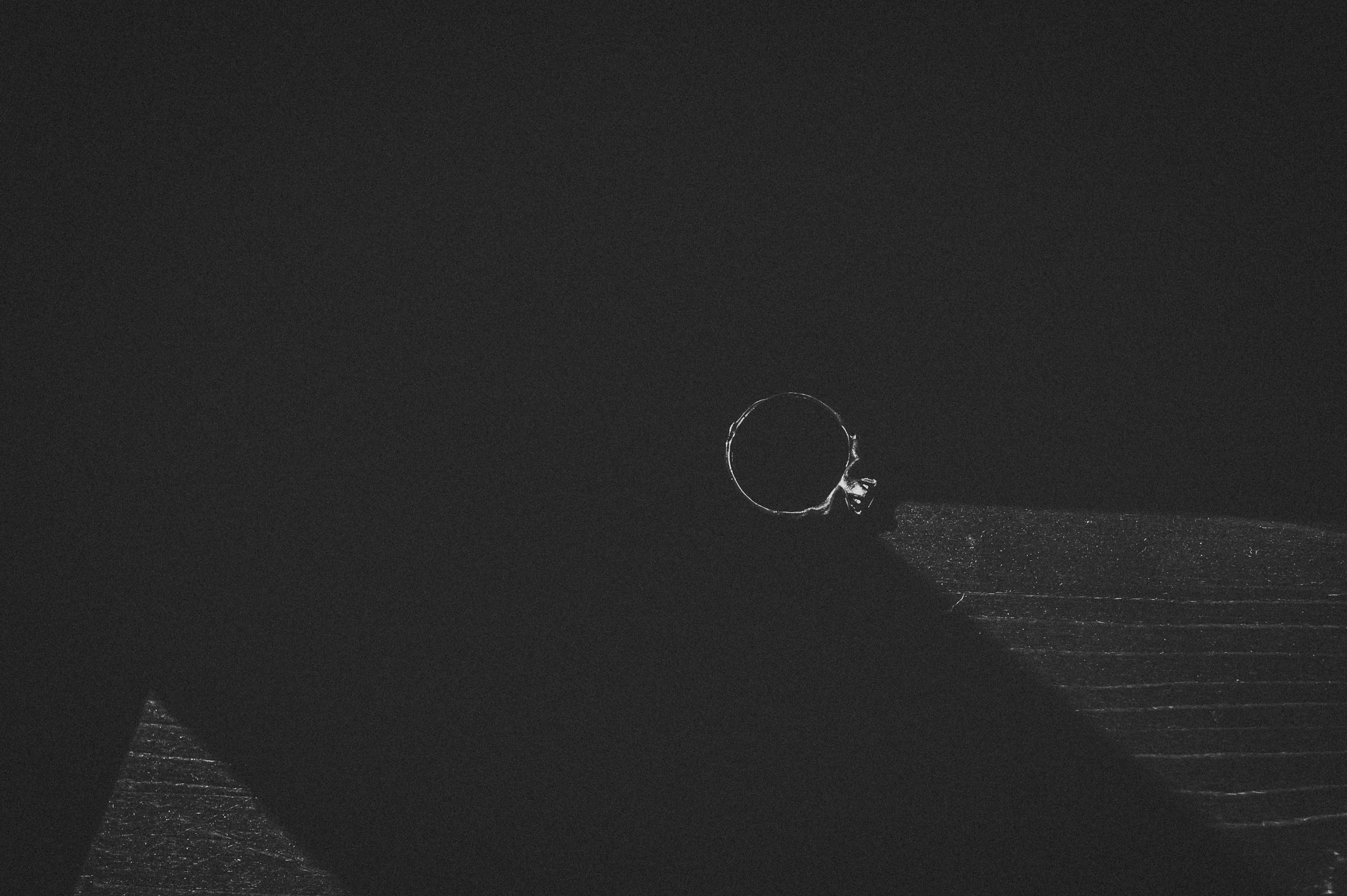 Detaliu alb-negru cu inelul de logotna asezat pe masa in lumina soarelui