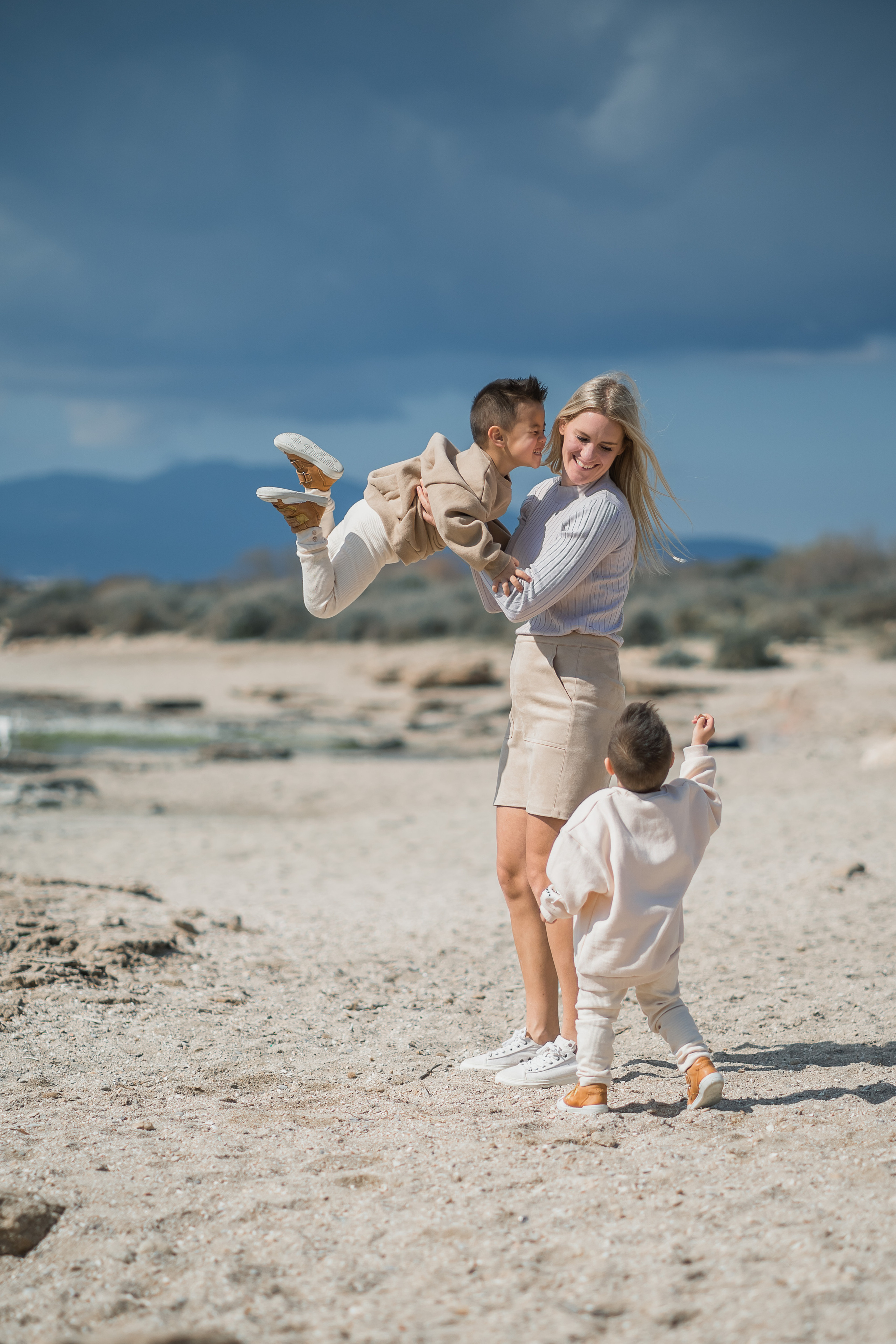 Eine Mutter, die mit ihren Kindern am Strand von Arenal lacht und spielt
