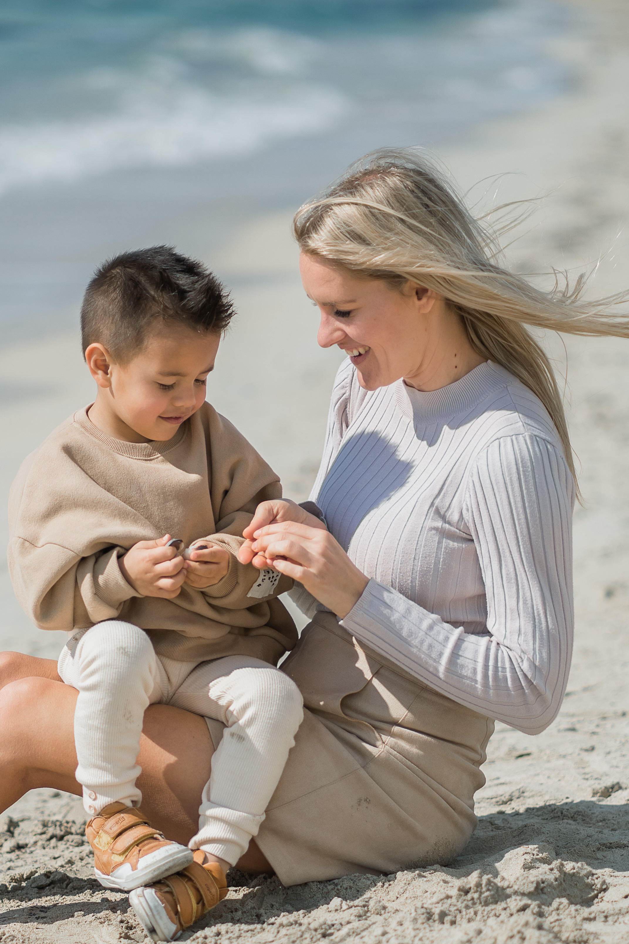 Eine Mutter, die mit ihrem Sohn am Strand von Playa de Palma Muscheln sammelt