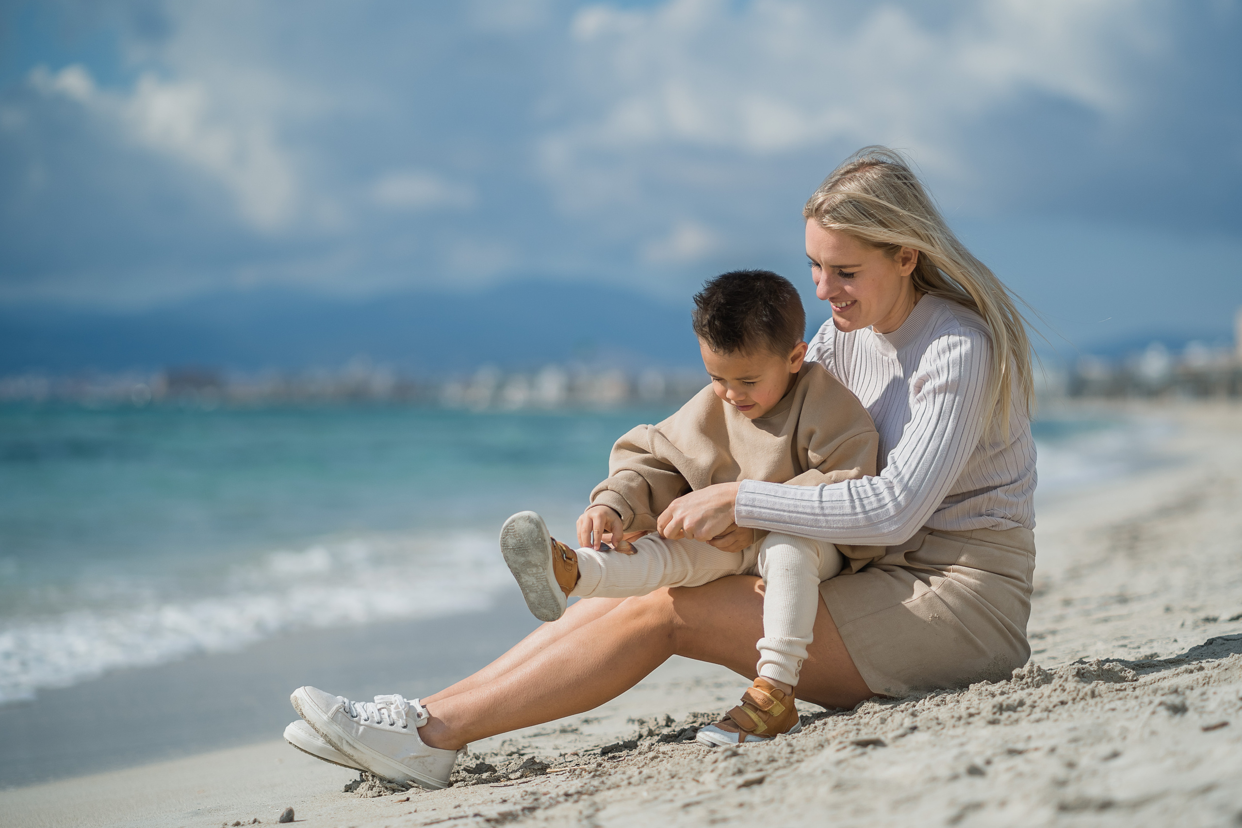 Eine Mutter, die mit ihrem Sohn am Strand von Playa de Palma im Sand spielt