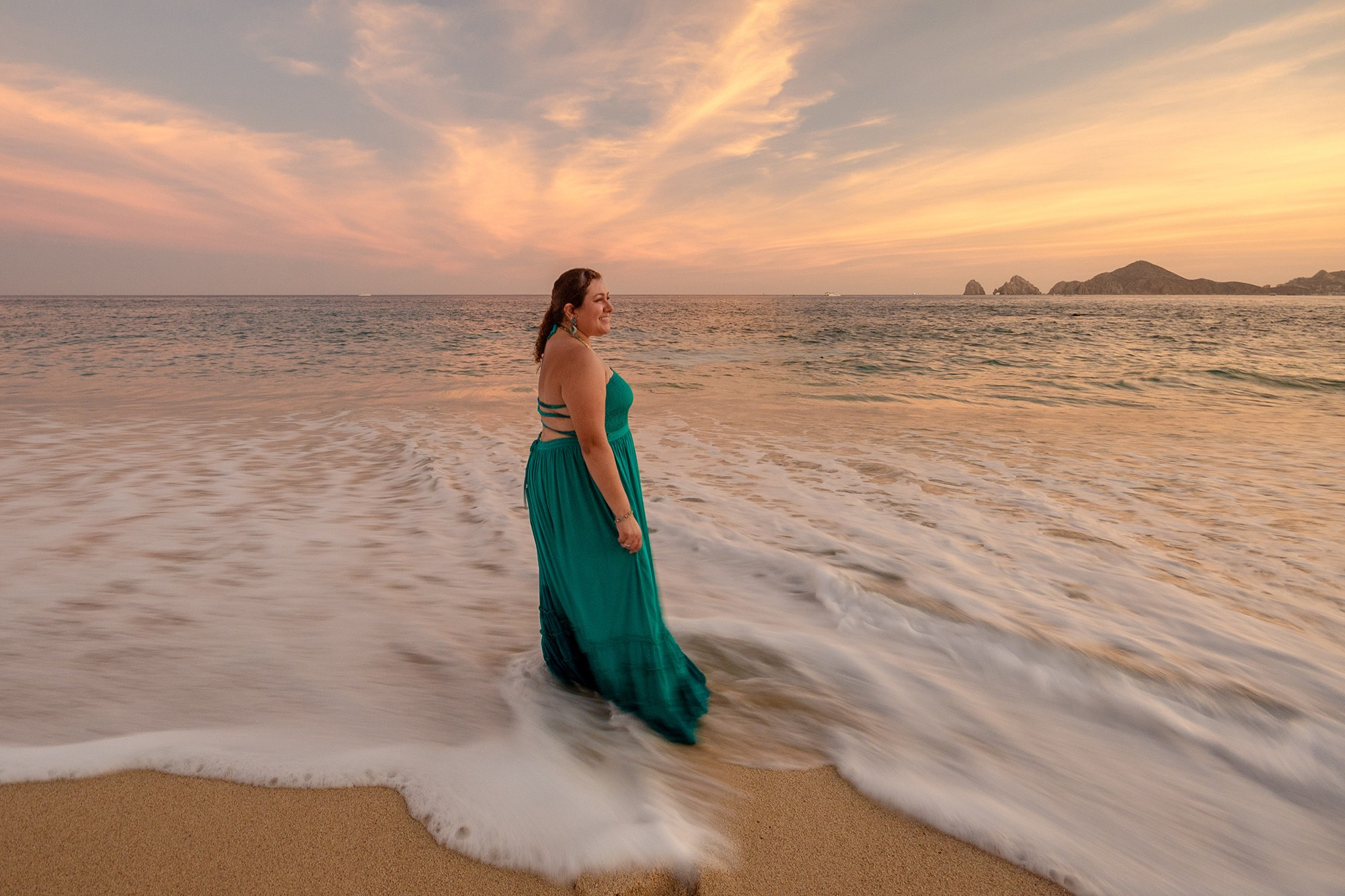 Woman in long green dress standing at ocean shoreline during lifestyle session in Cabo San Lucas