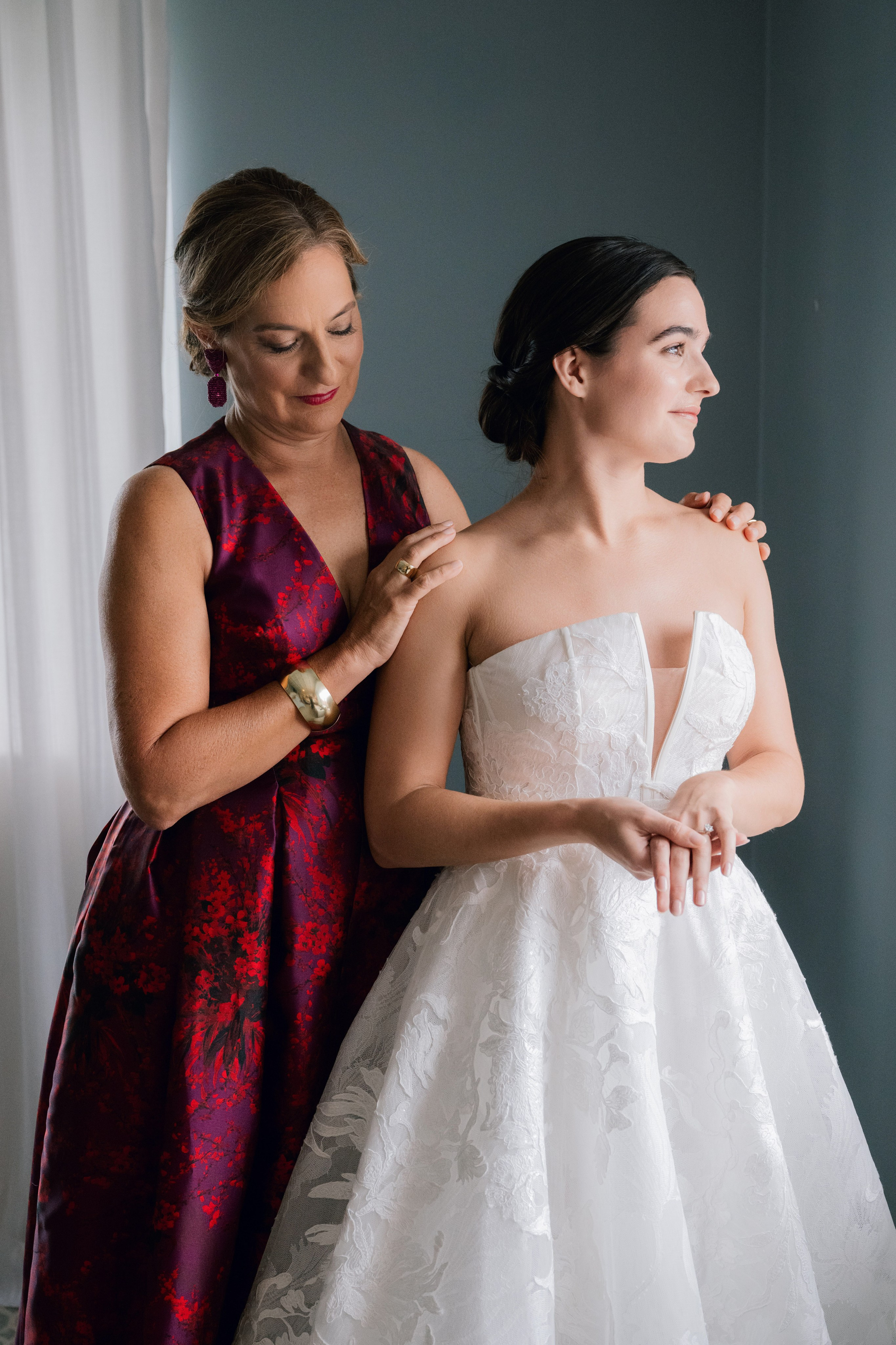 a woman in a wedding dress helping another woman with her dress