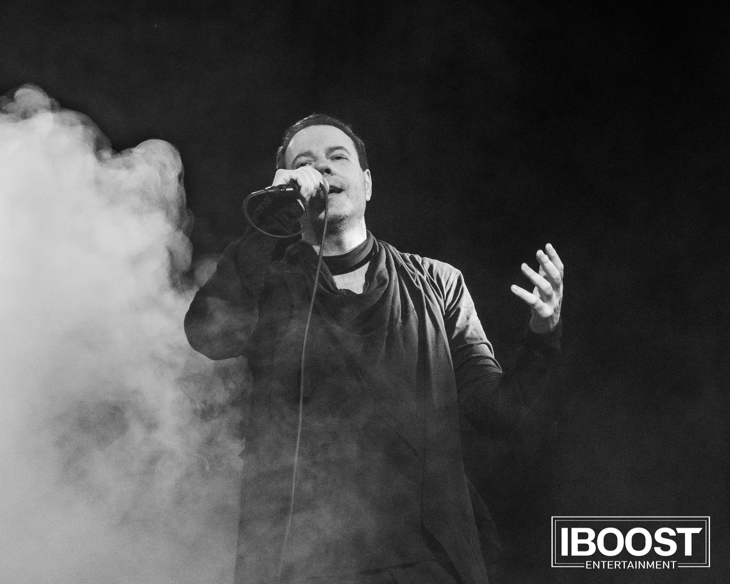 Black-and-white close-up of the lead vocalist of Animal JazZ singing on stage surrounded by smoke.