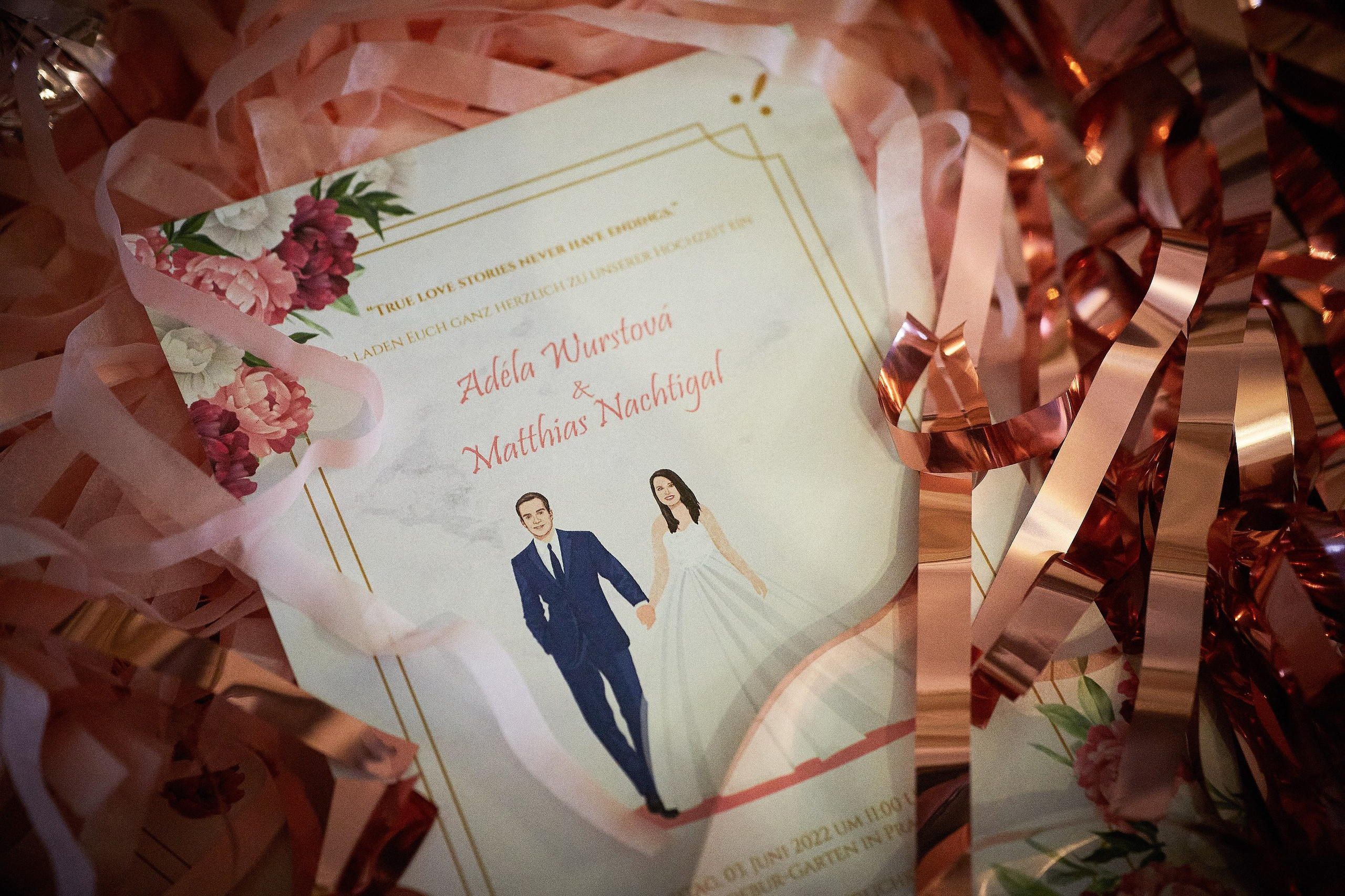 A wedding invitation with the couple's name is surrounded by glitter.
