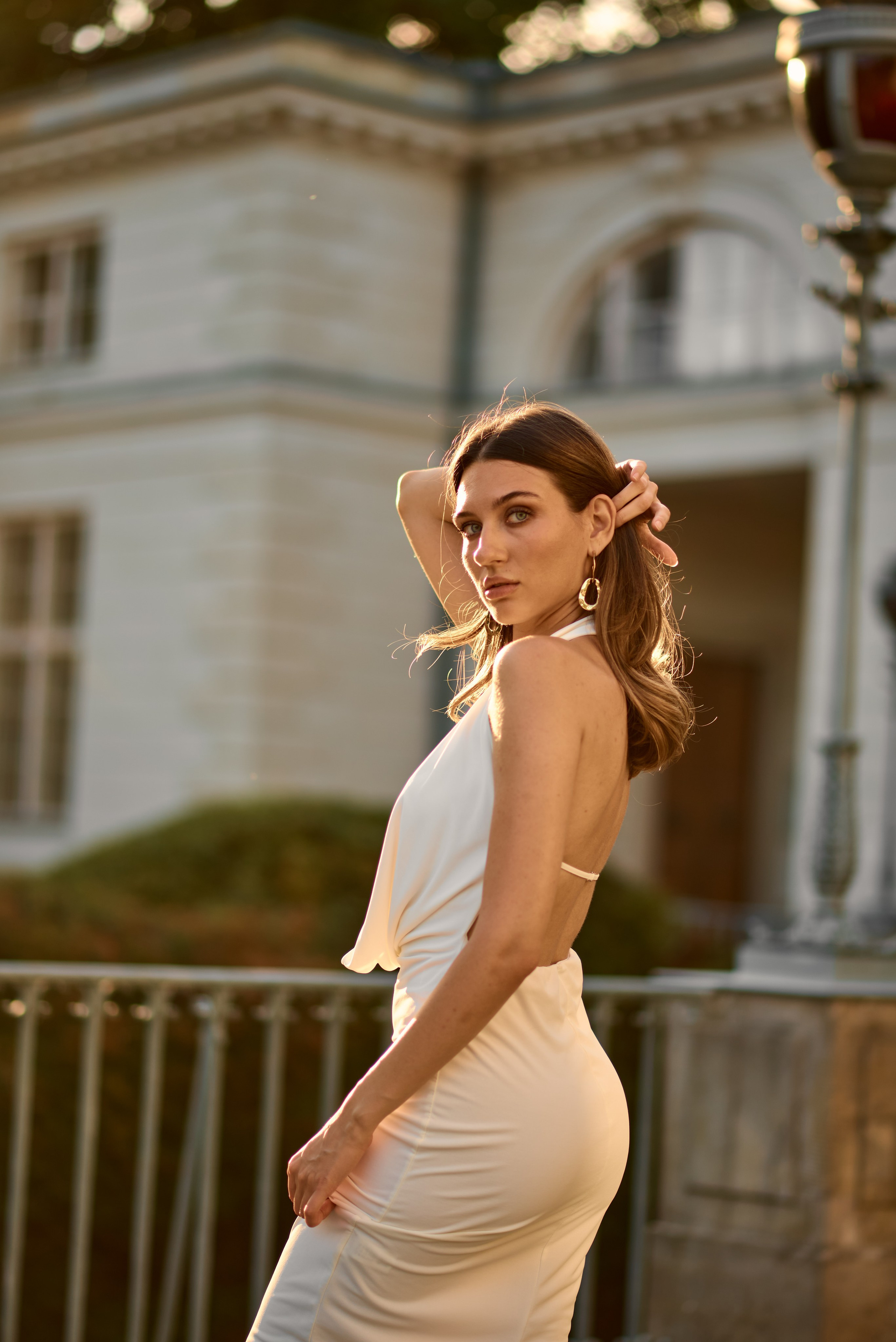 7️⃣ Близький портрет моделі в білосніжній сукні, її пронизливий погляд ловить останні сонячні промені, створюючи теплу атмосферу.
