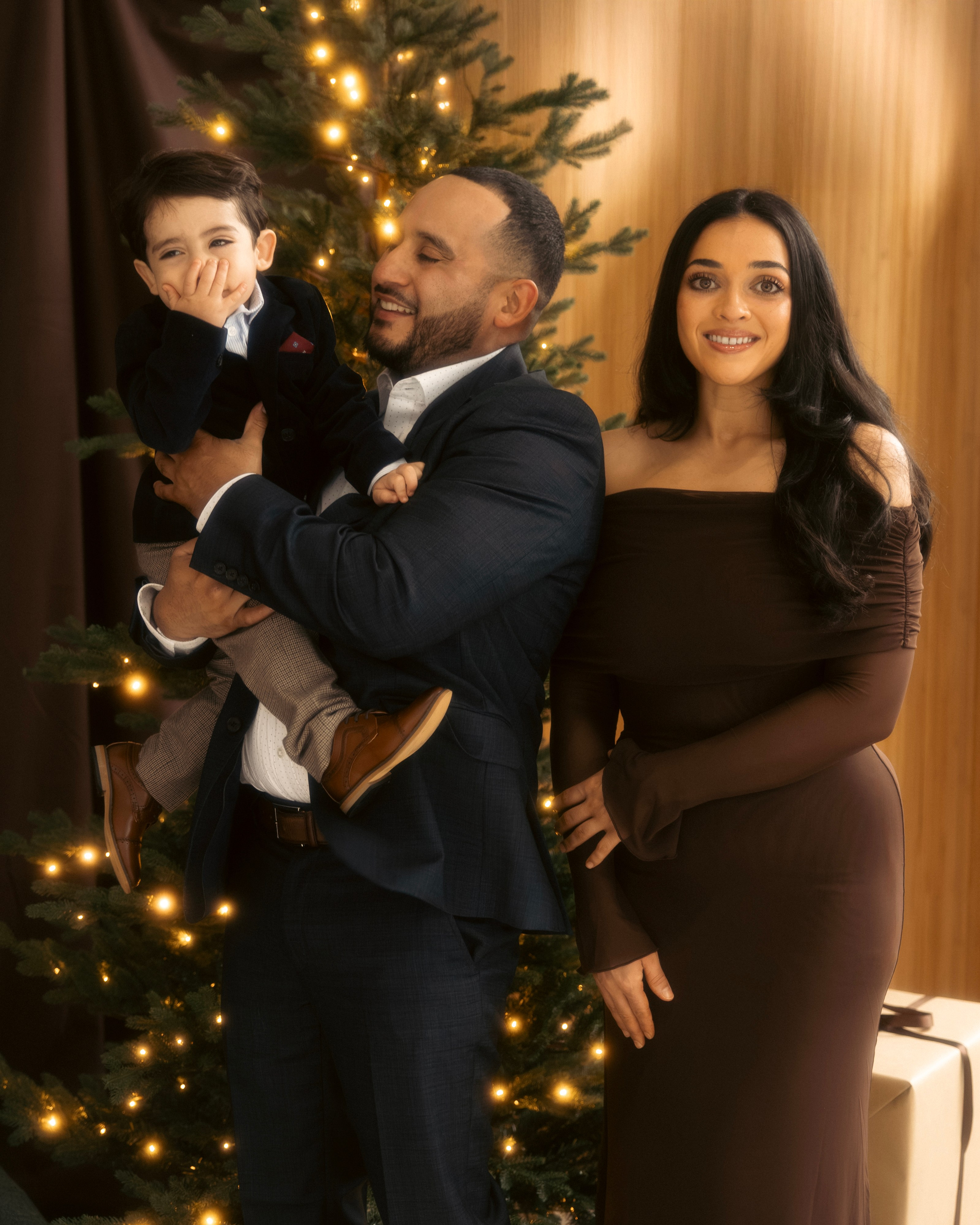 Parents lifting child while decorating Christmas tree in holiday studio