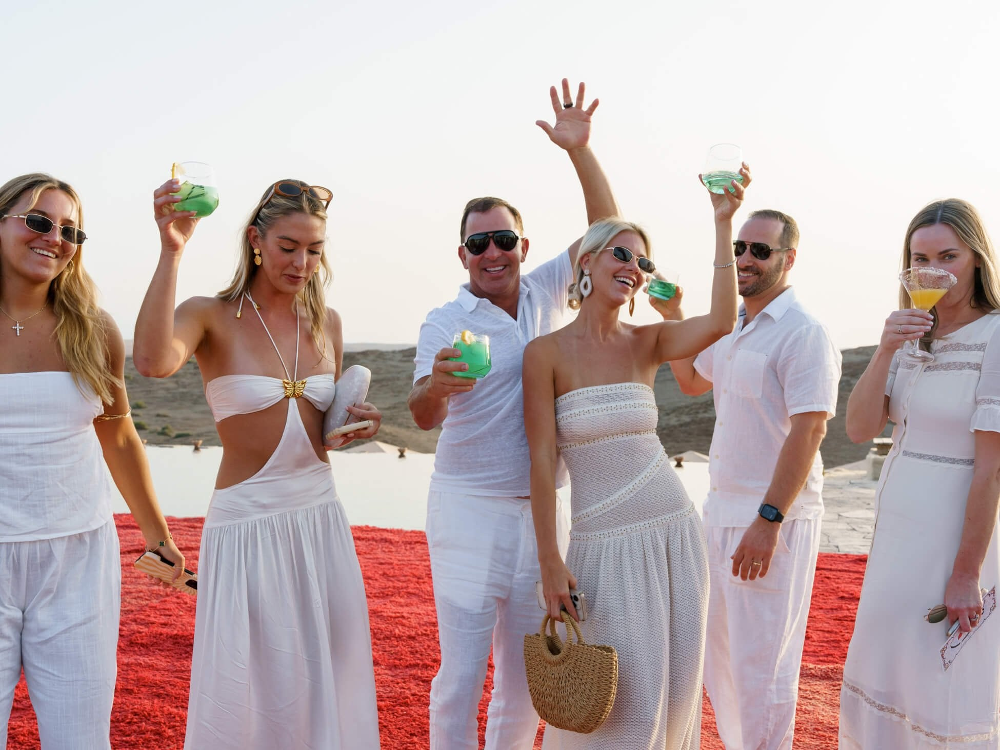 Guests raising drinks during luxury destination desert wedding welcome party, Morocco