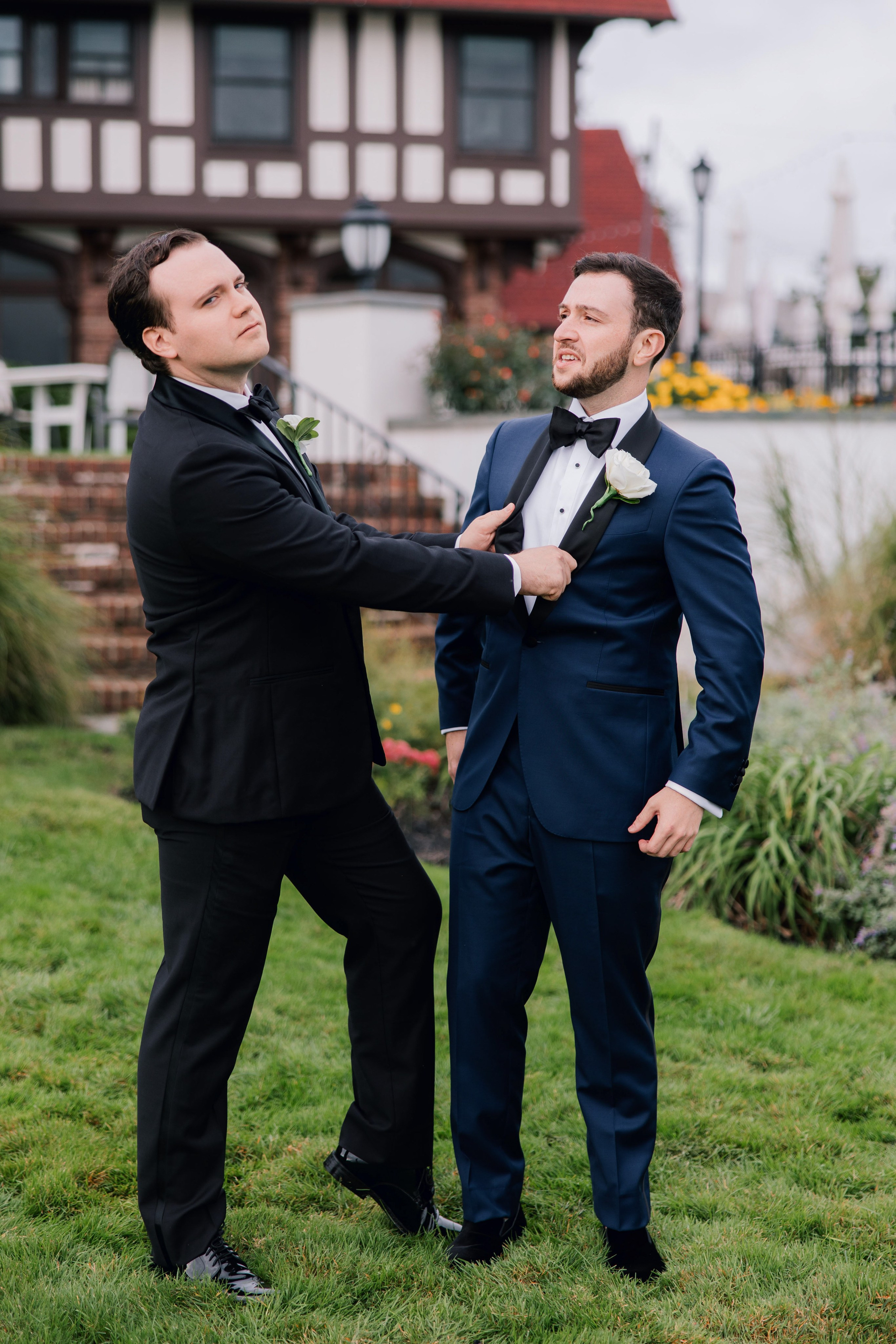a man in a suit and tie is helping another man in a suit