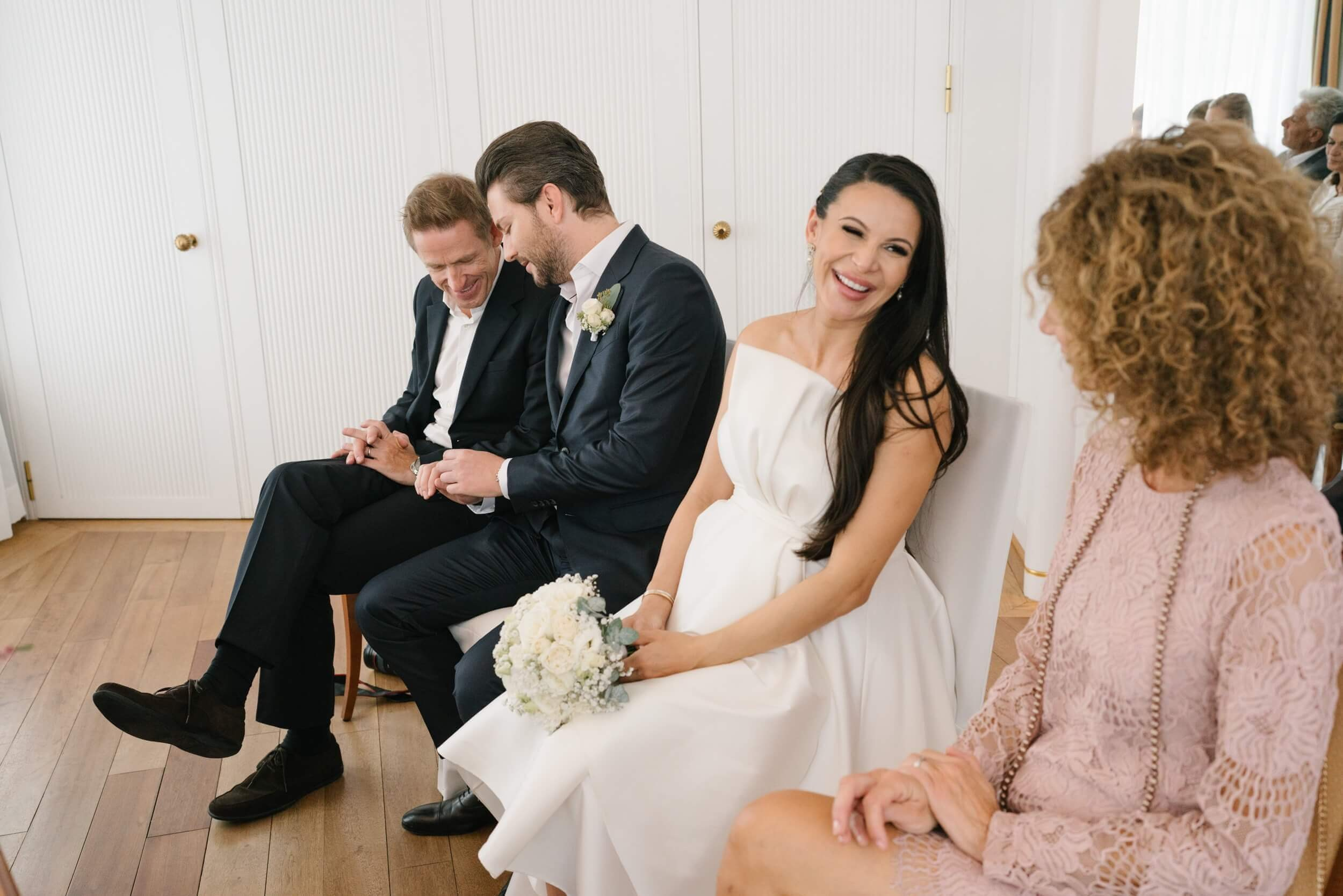 Couple seated with bouquet during ceremony at Standesamt Grünwald