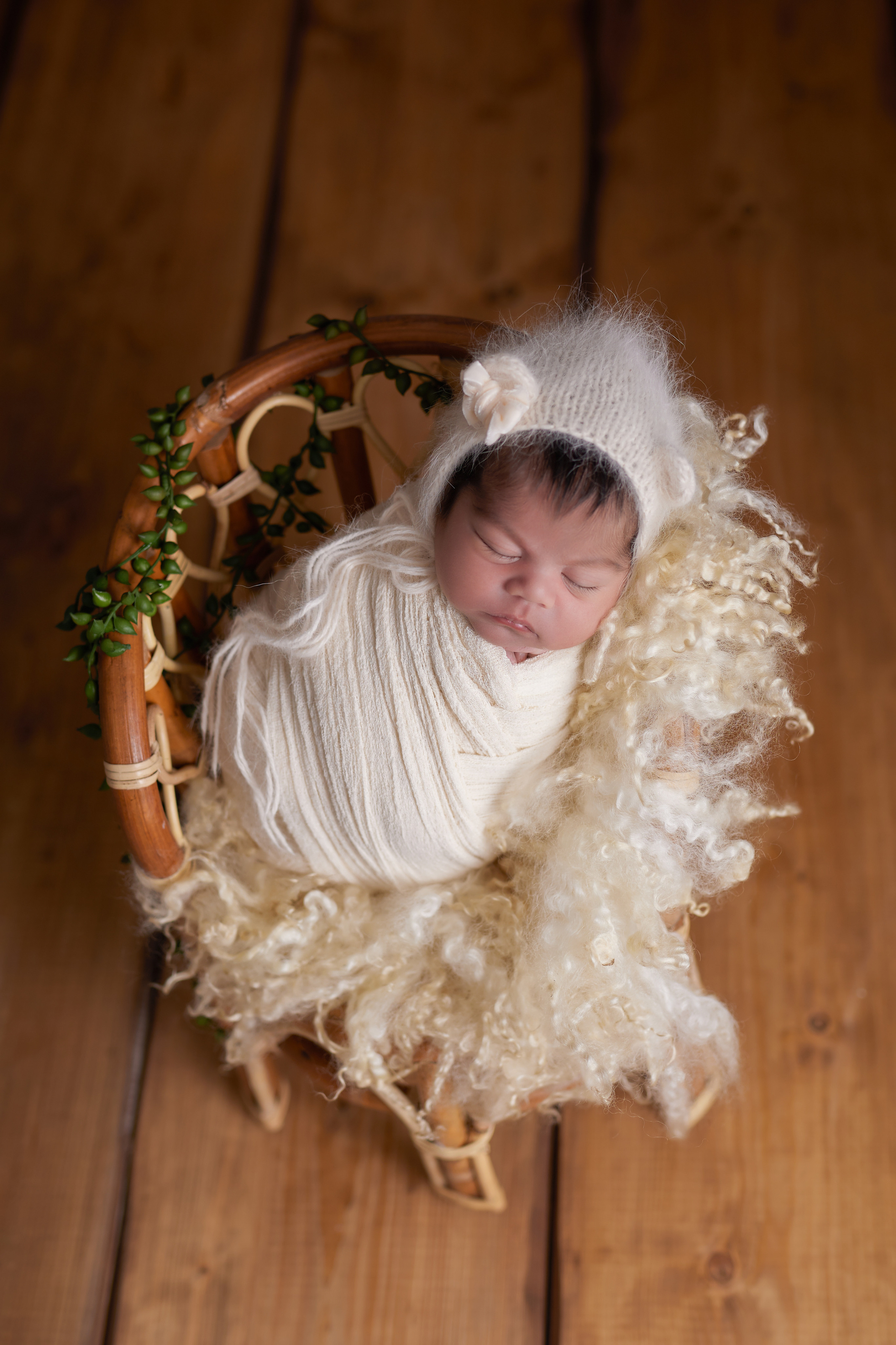 Frisch geborenes Baby eingewickelt in eine Decke, liegt in einem rustikalen Körbchen – Newbornfotografie in Iserlohn